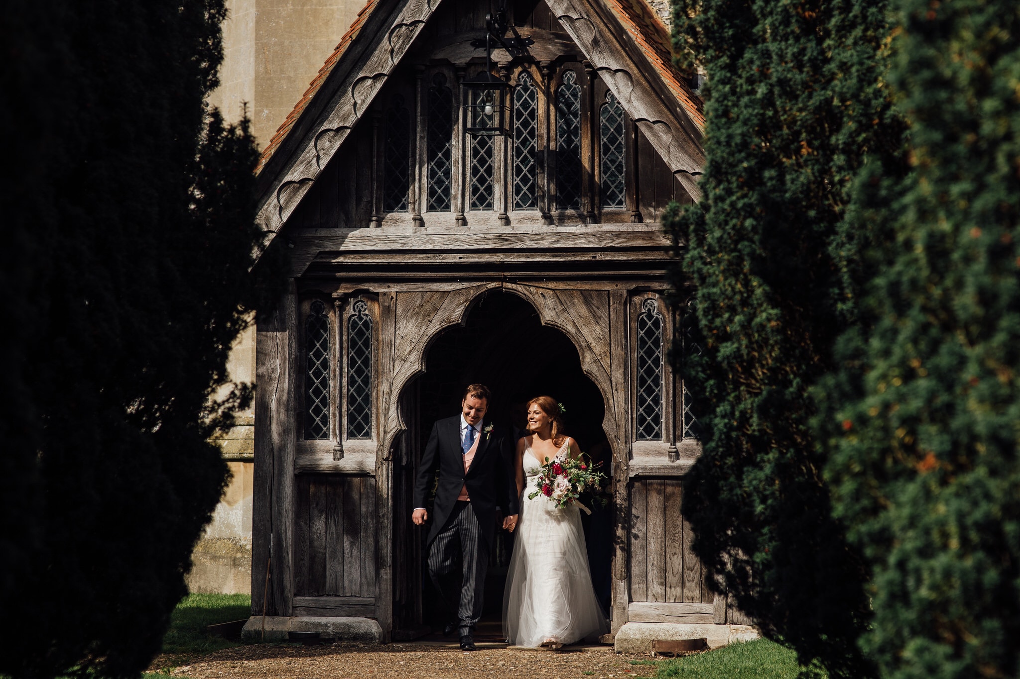 golden light as bride and groom exit church smiling