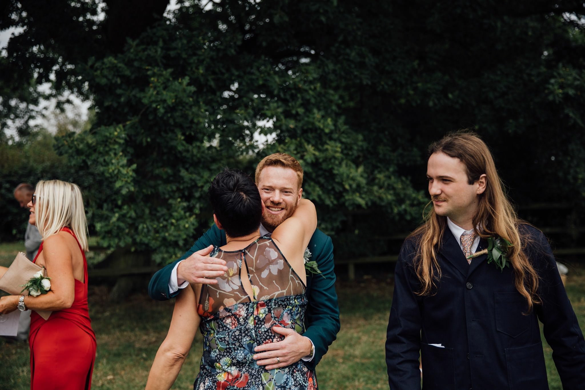 documentary style wedding photography groom hugging guest