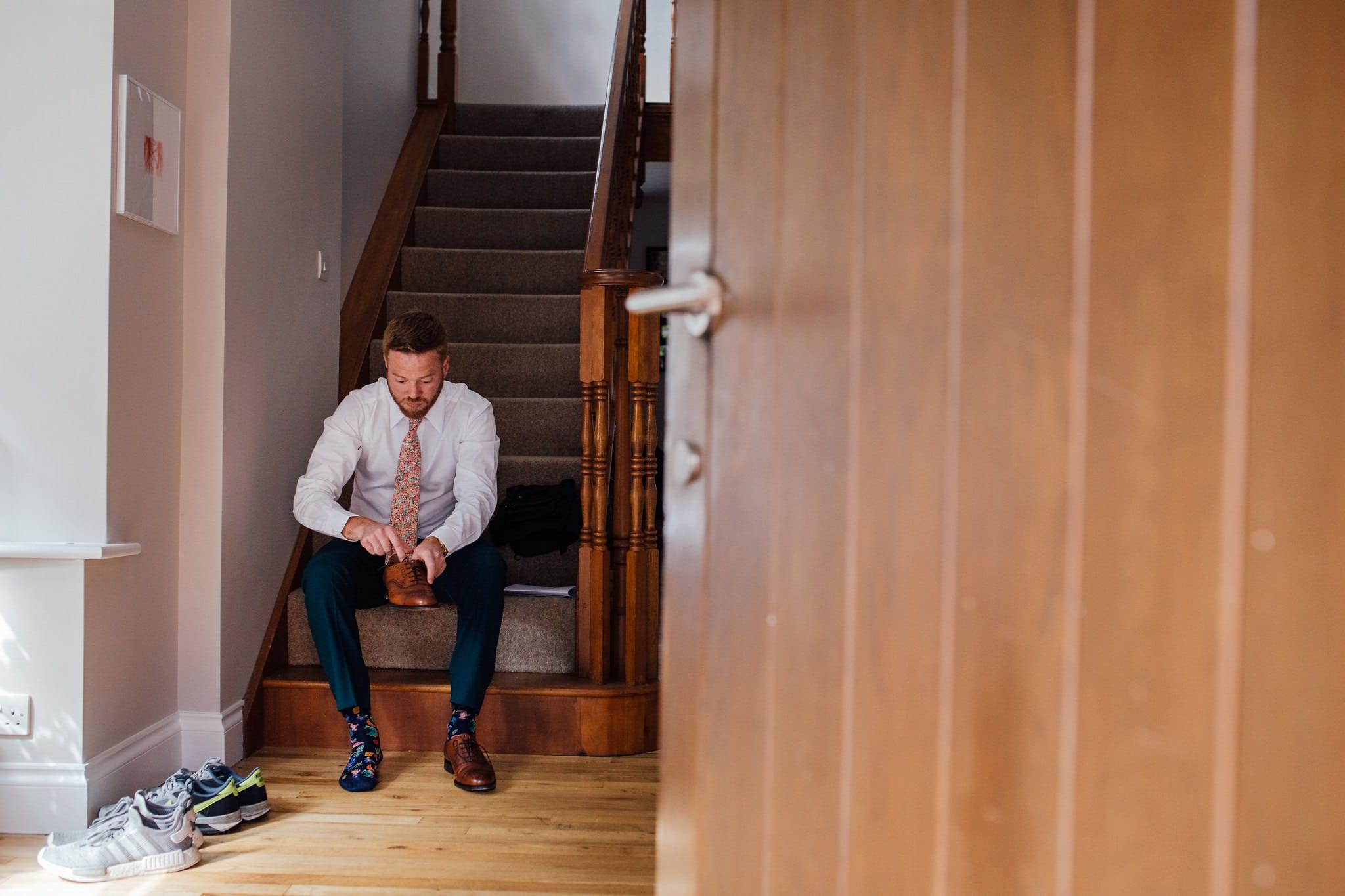 groom putting brogues on with colourful socks