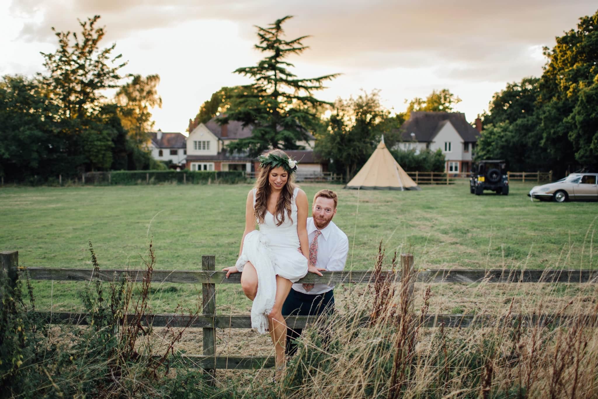 bride and groom jumping the fence for perfect wedding photos