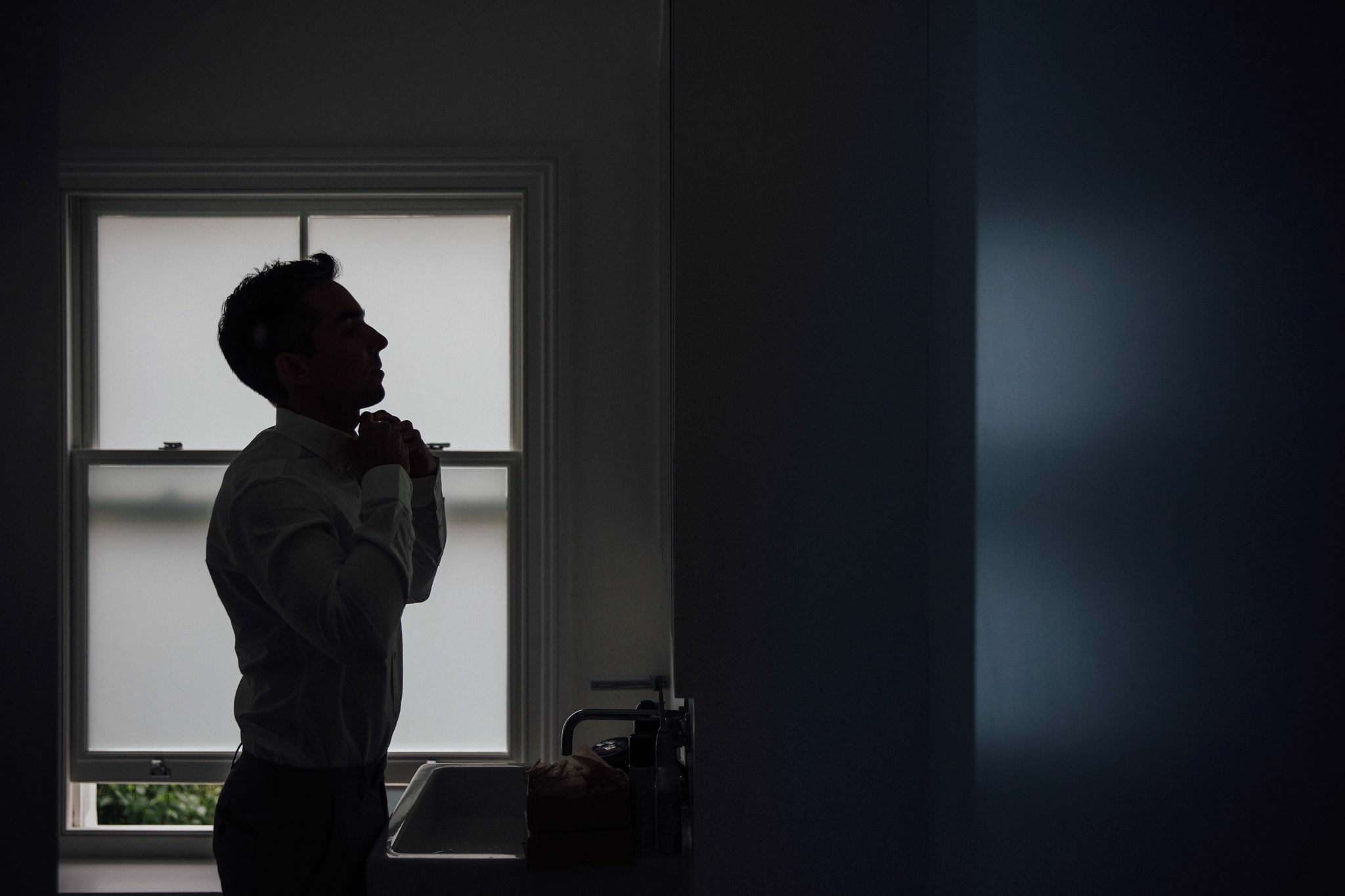 silhouette groom putting on bow tie