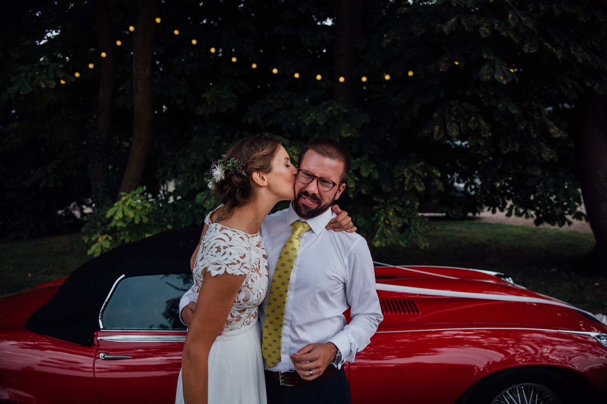 bride and groom evening portrait red car