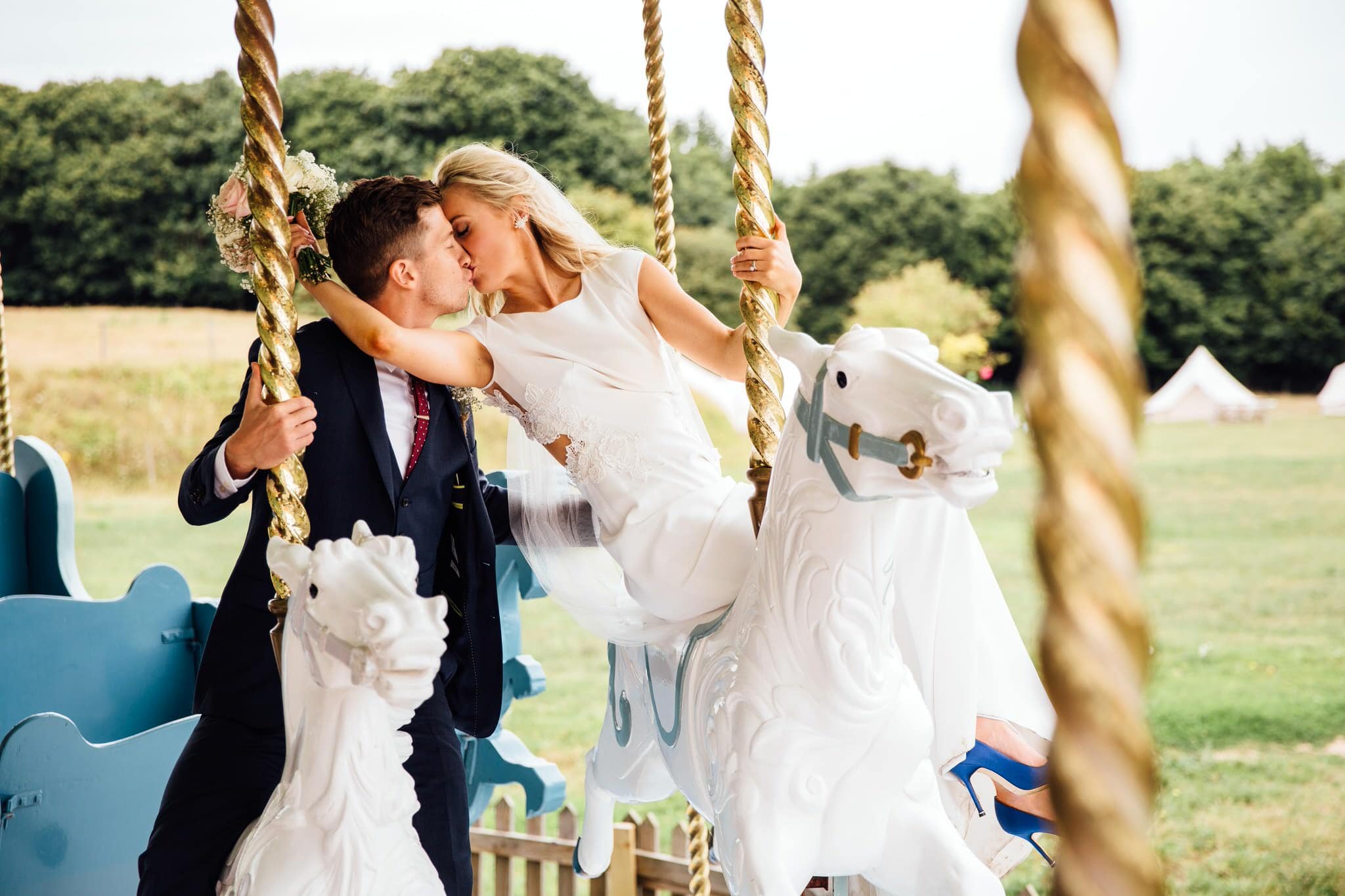 bride and groom kiss on carousel
