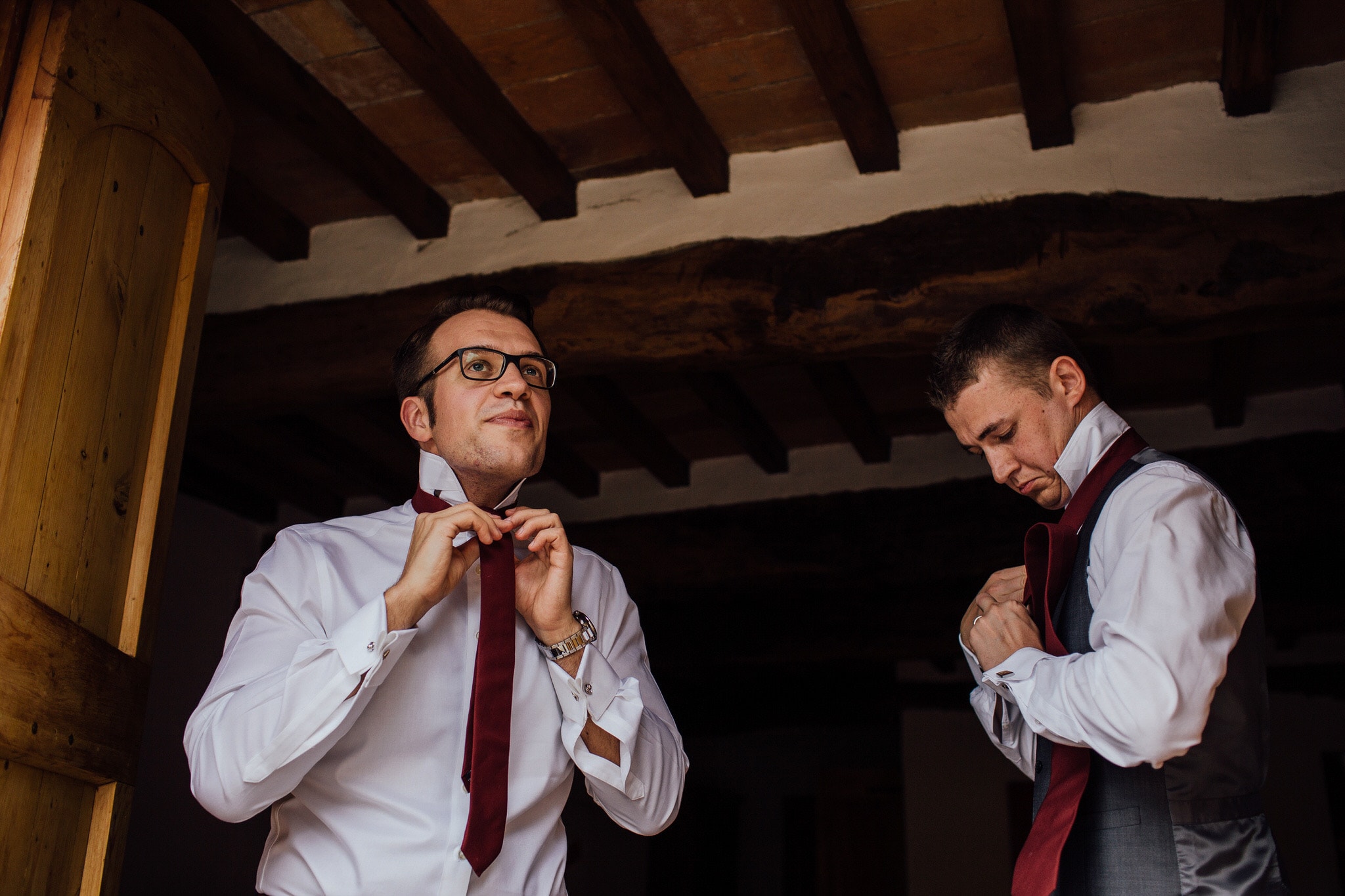 Groom putting tie on in doorway of Castello di Bibbione