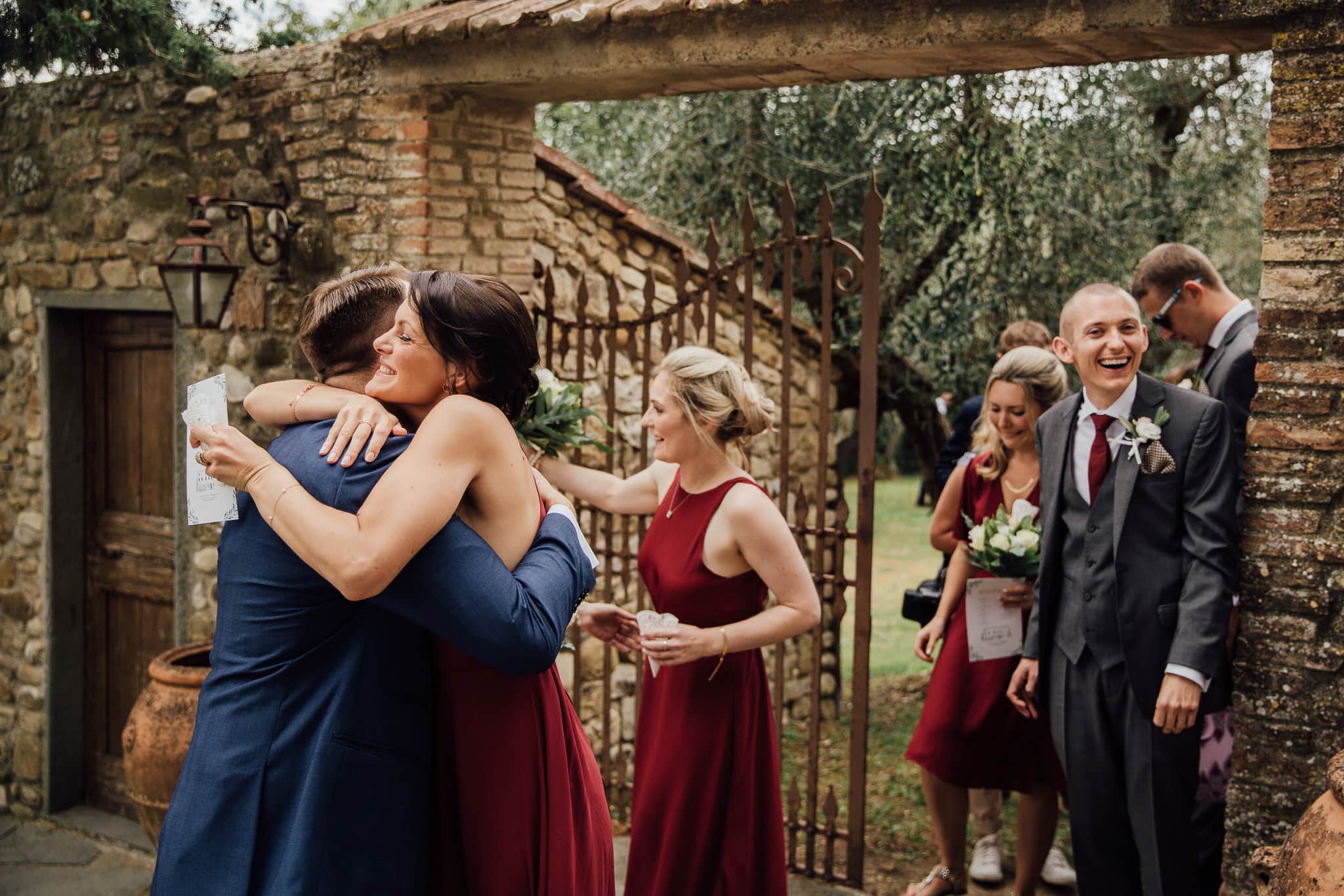 Bridesmaid in red dress hugging groom