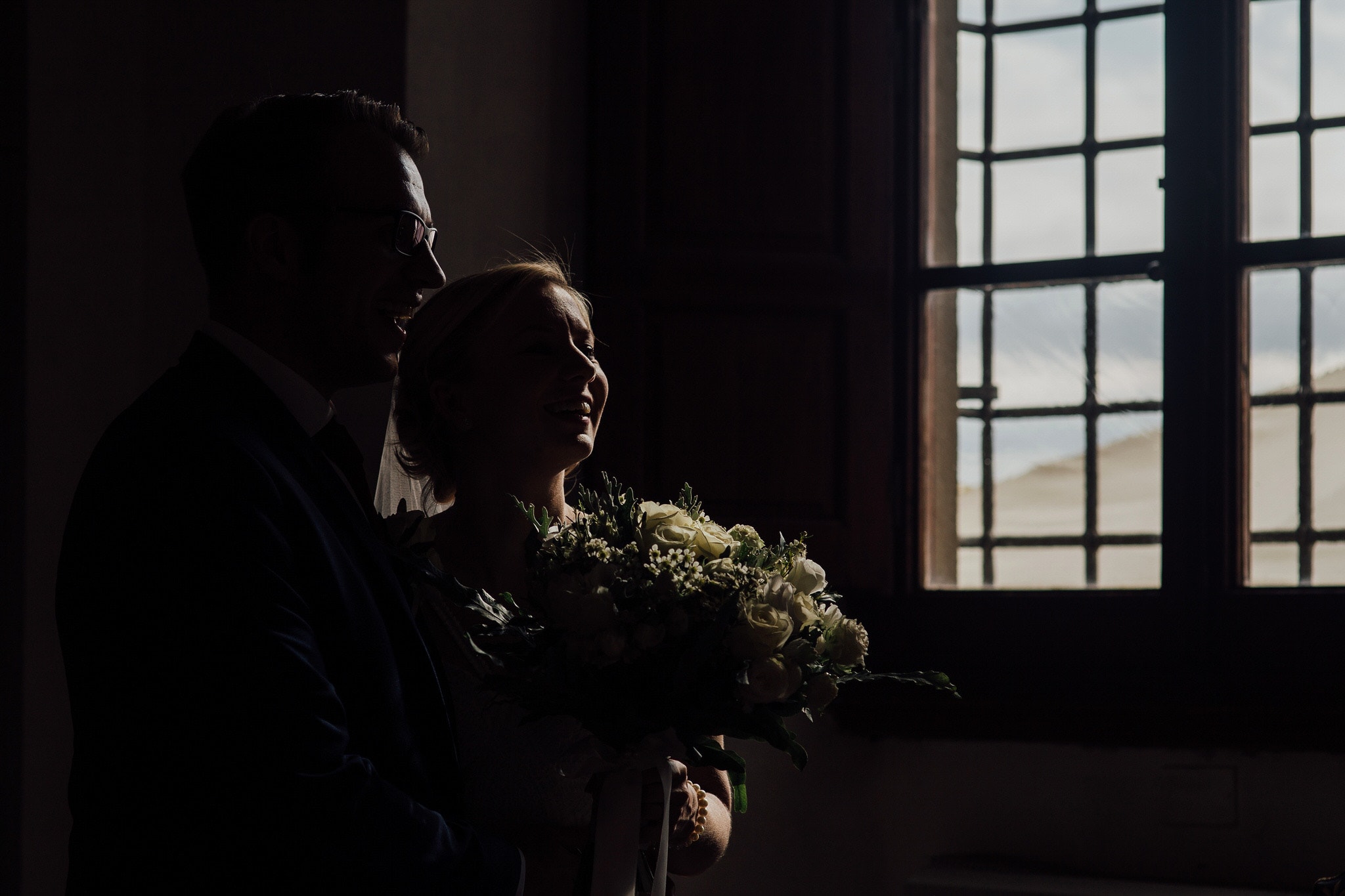 bride and groom laughing catching highlights from window light
