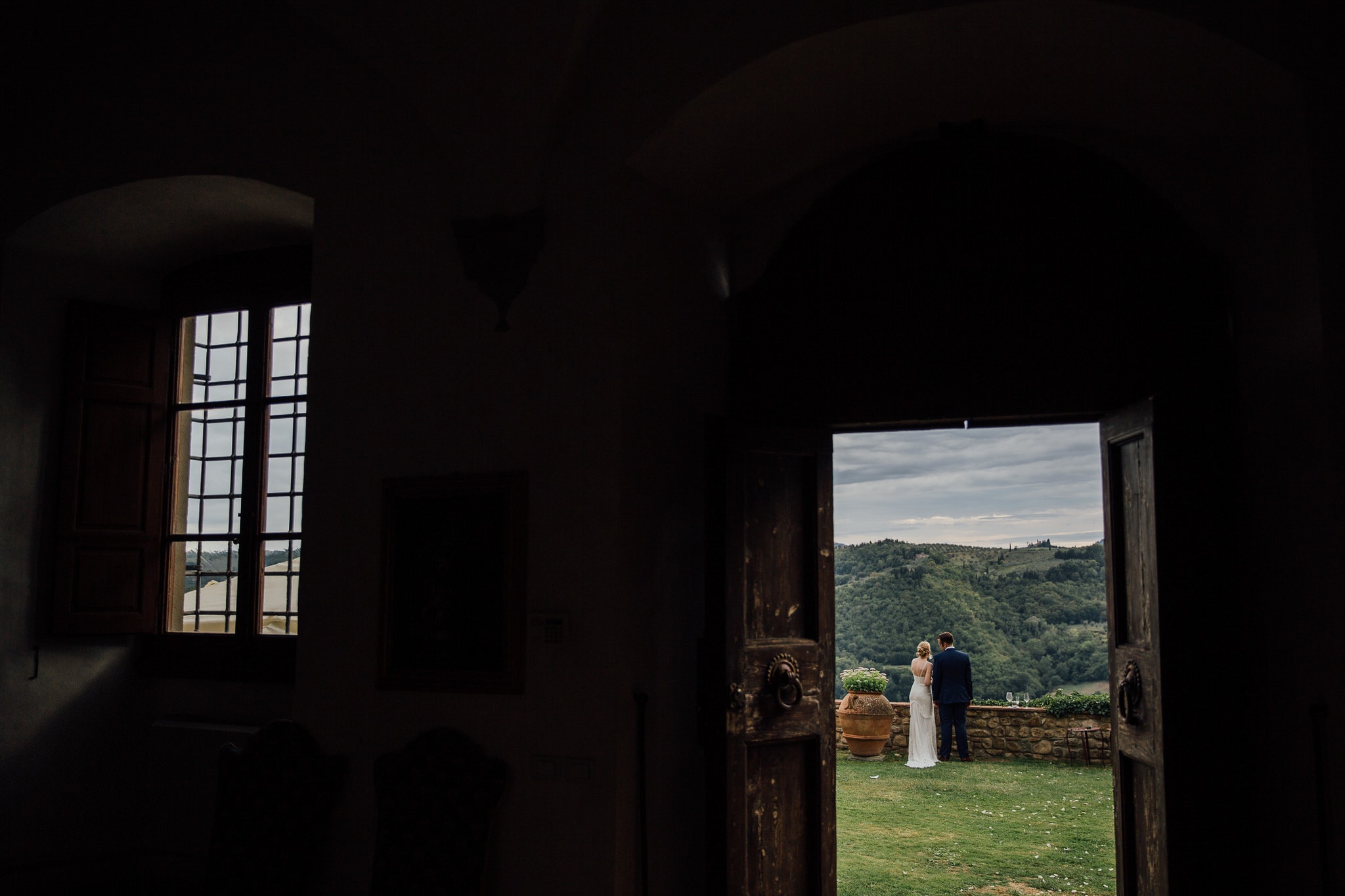 shot through doorway framing bride and groom looking at view of Tuscan hills