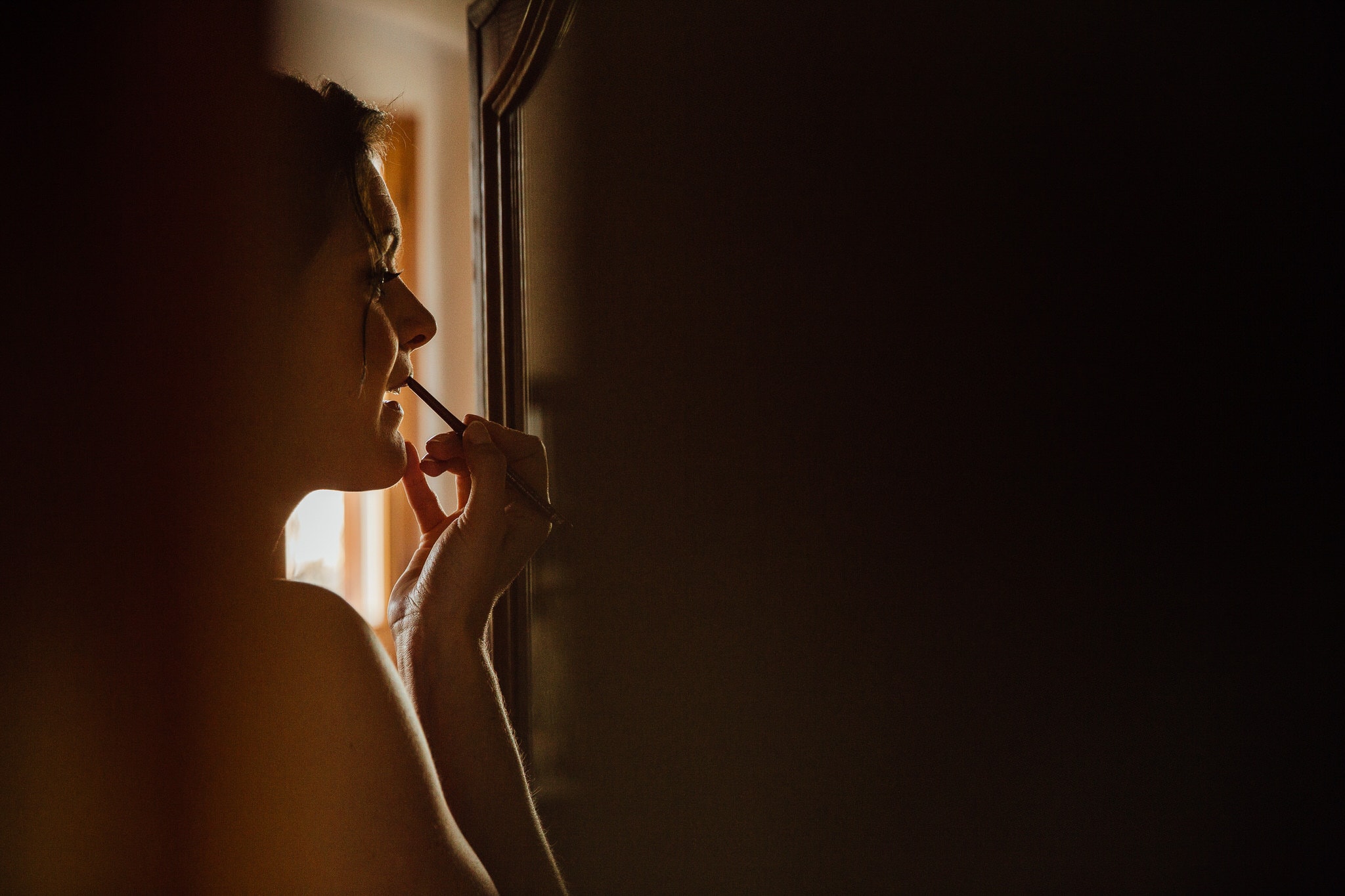 close up of bridesmaid in shadows putting on lipstick