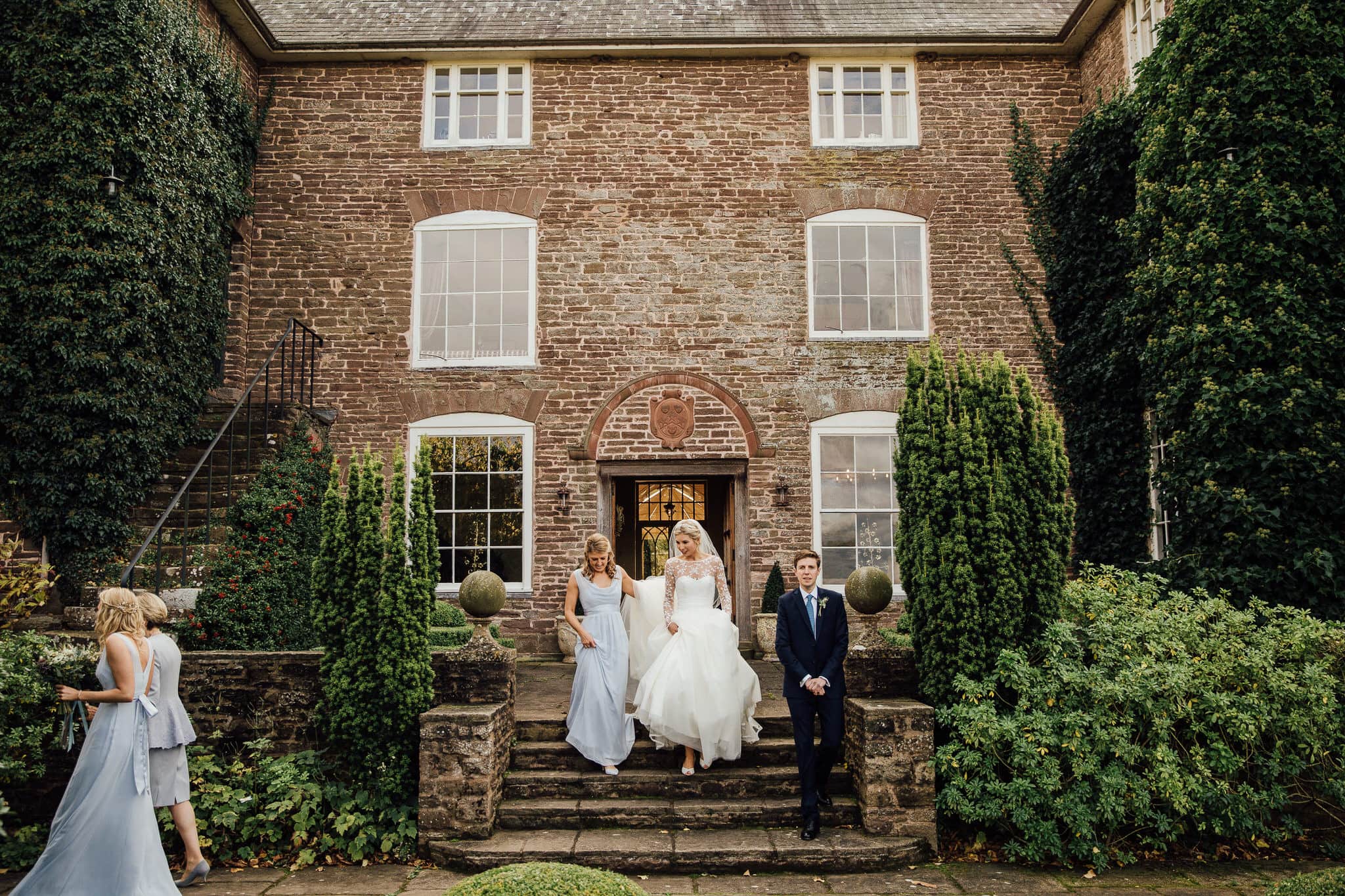 bride and bridesmaids walk to ceremony at Dewsall Court