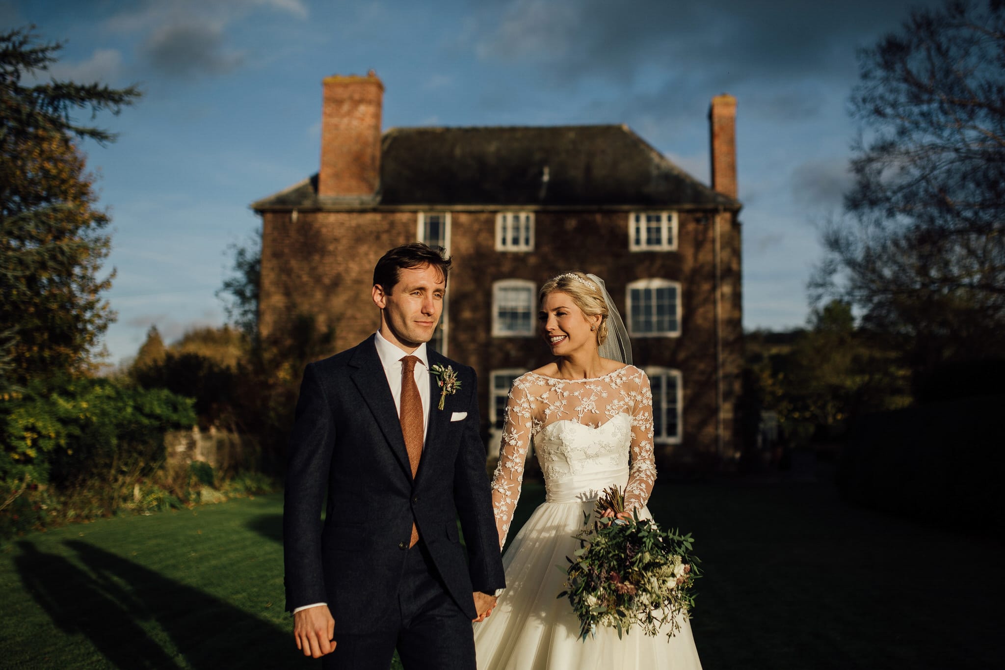 bride and groom walking in golden sunshine at Dewsall Court