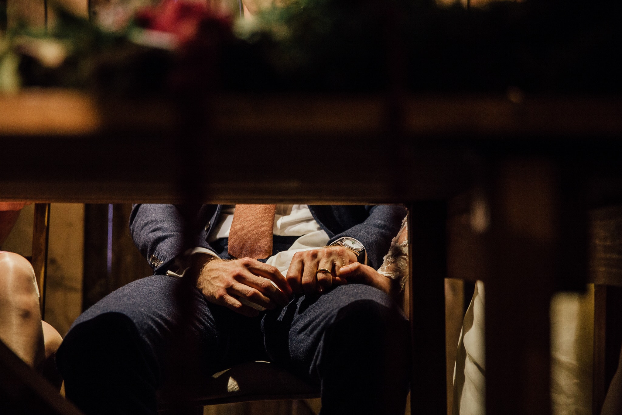 bride squeezing groom's hand under the table during speeches