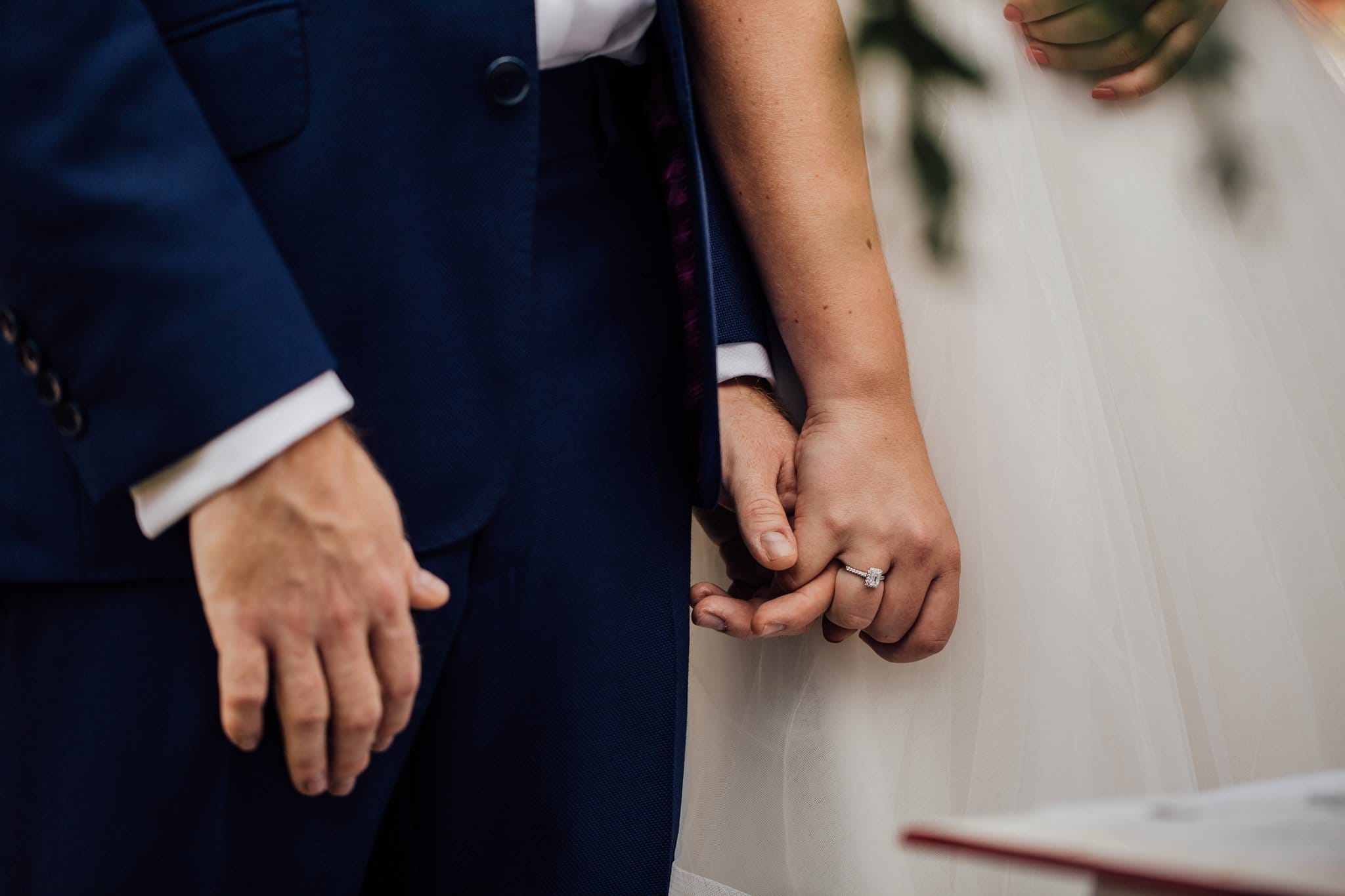 close up of bride and groom holding hands 