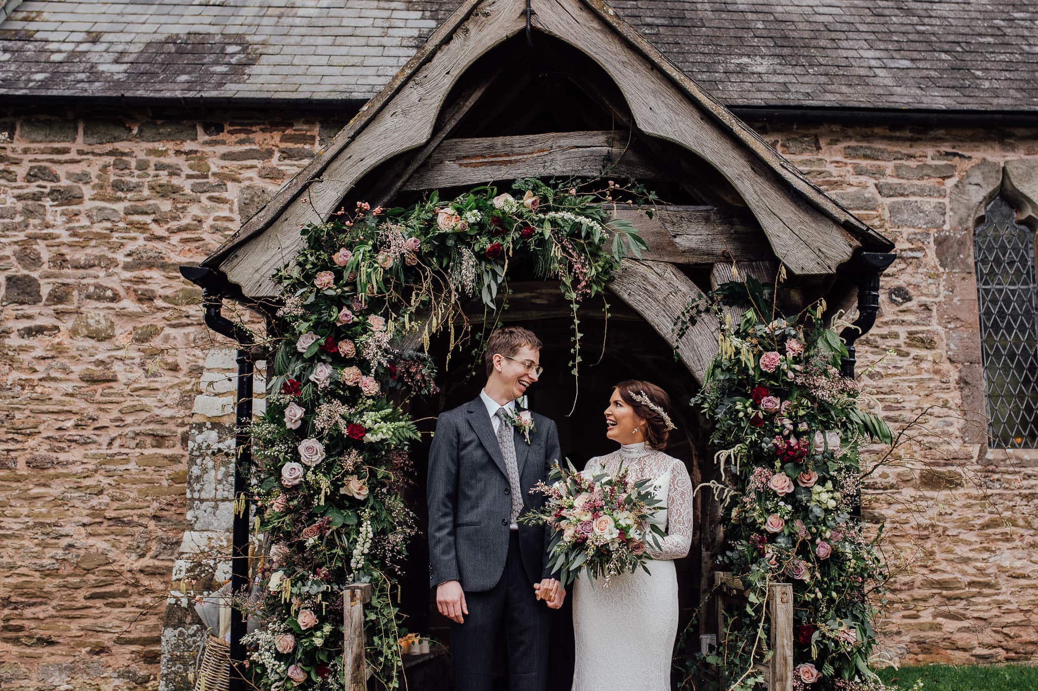 bride and groom framed by floral arch