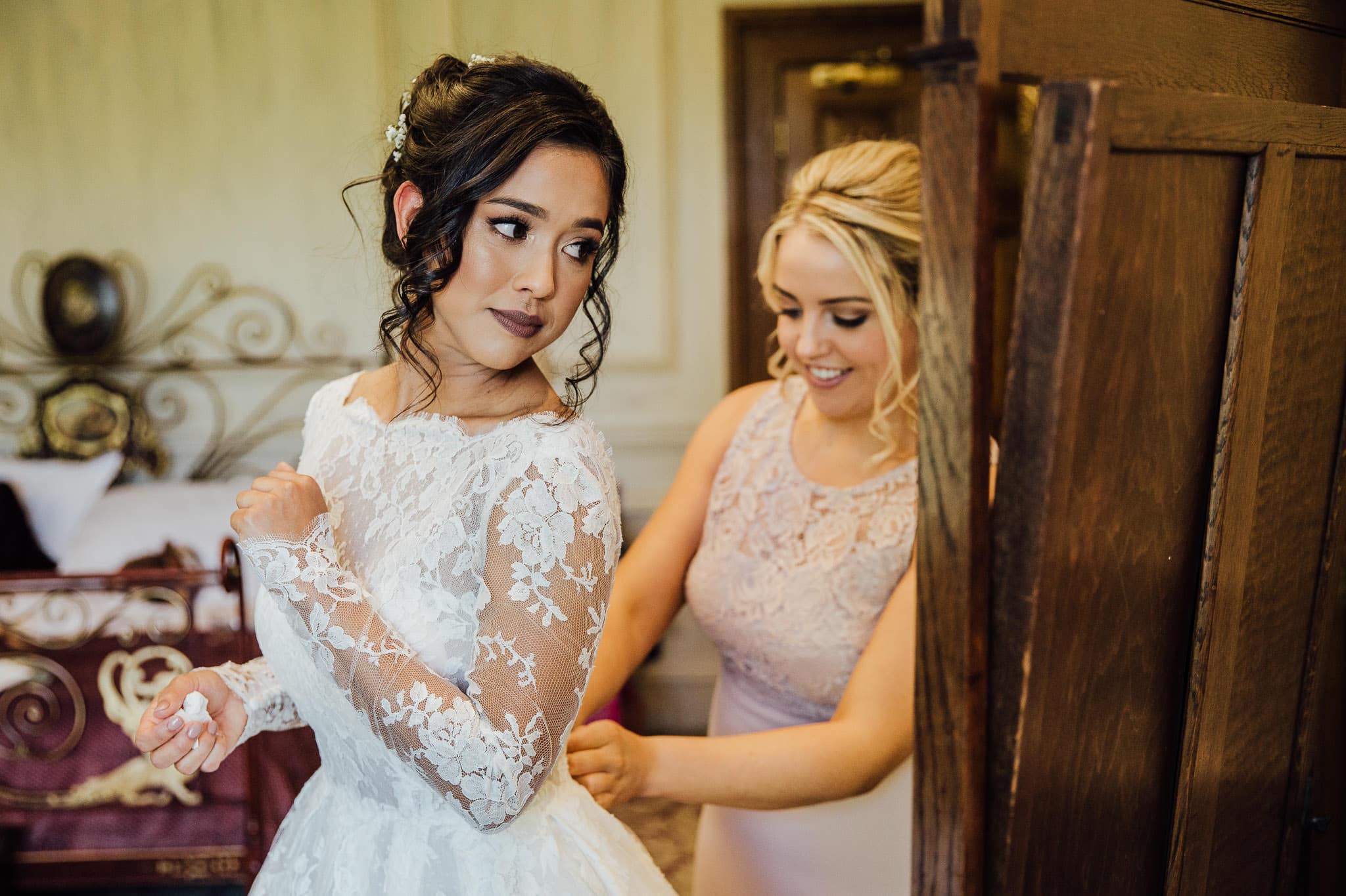 bride putting on lace long sleeved wedding dress