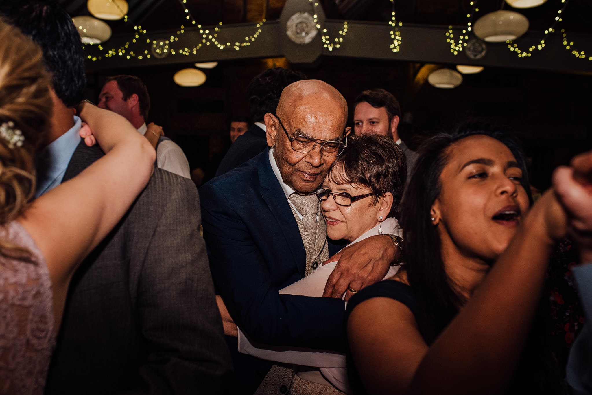 bride and grooms' parents cuddling on the dance floor