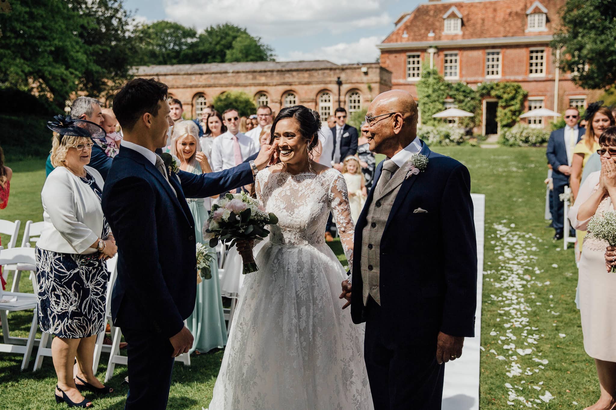 groom wipes a tear from his bride's cheek