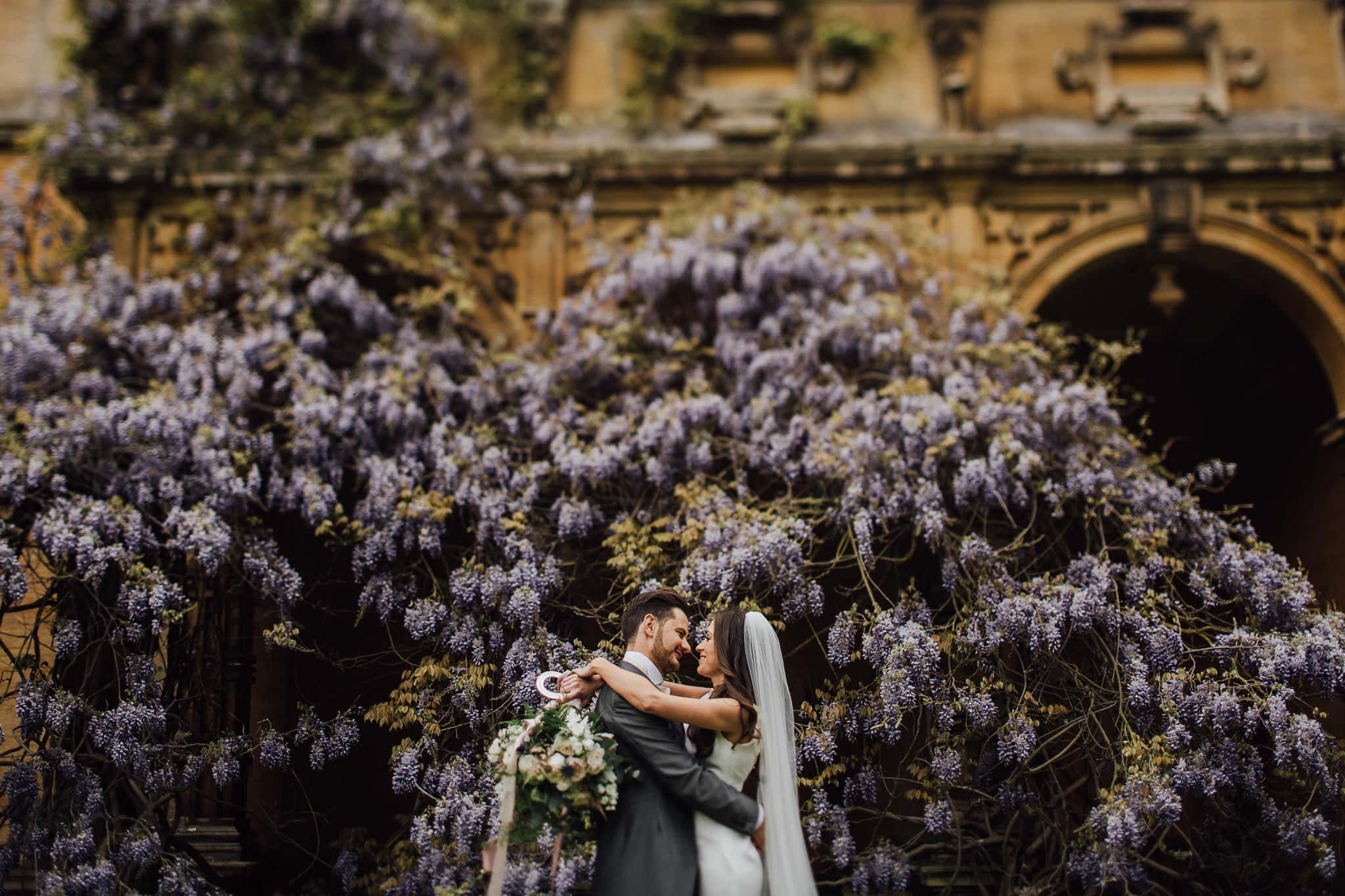 bride and groom under wisteria