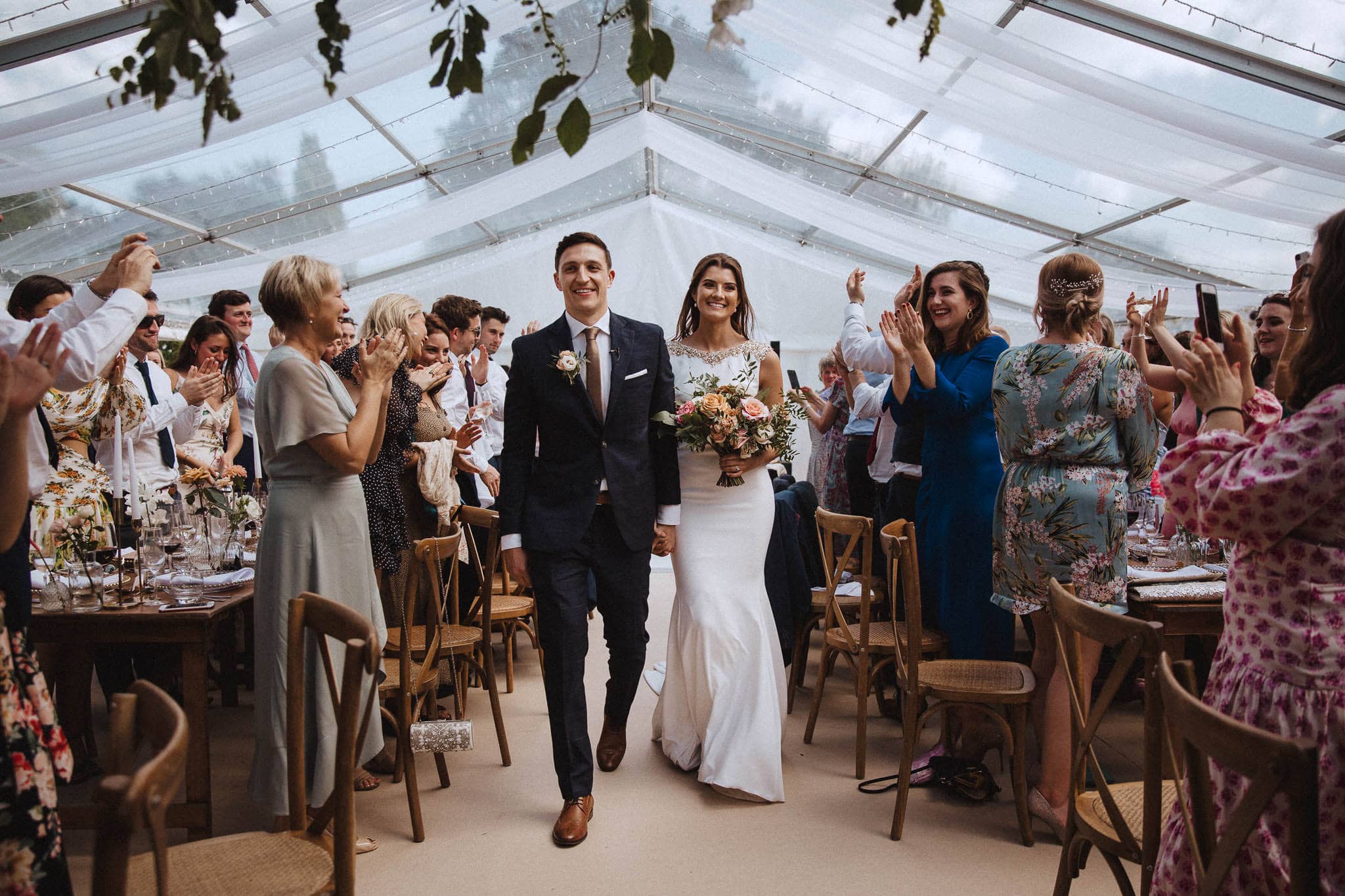 bride and groom enter the marquee at Sandon Hall wedding 