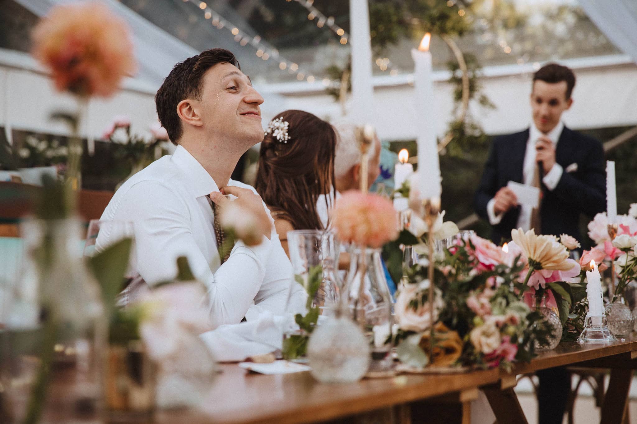 groom loosening his collar during the best man's speech