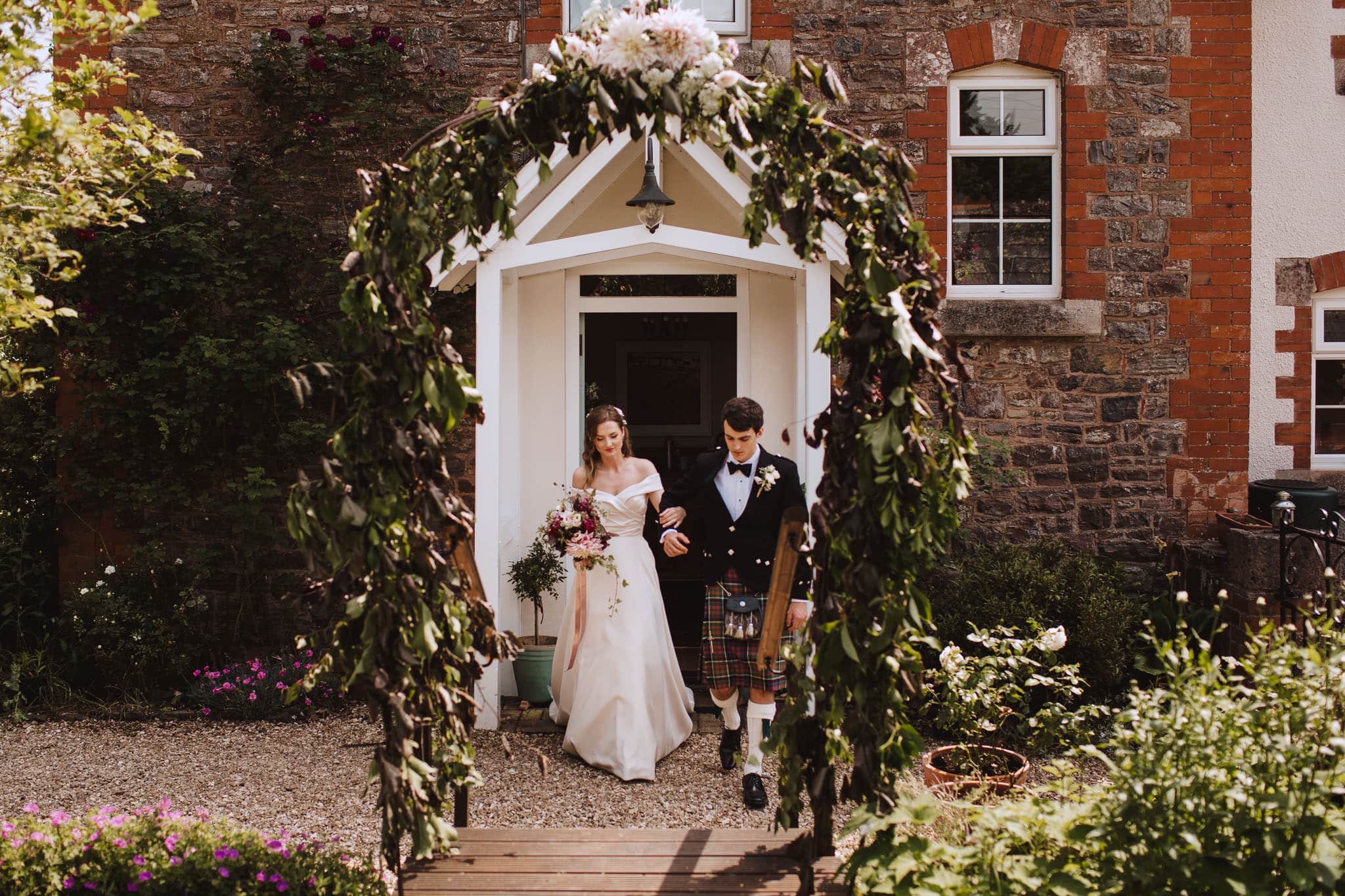 Bride enters outdoor ceremony through floral arch