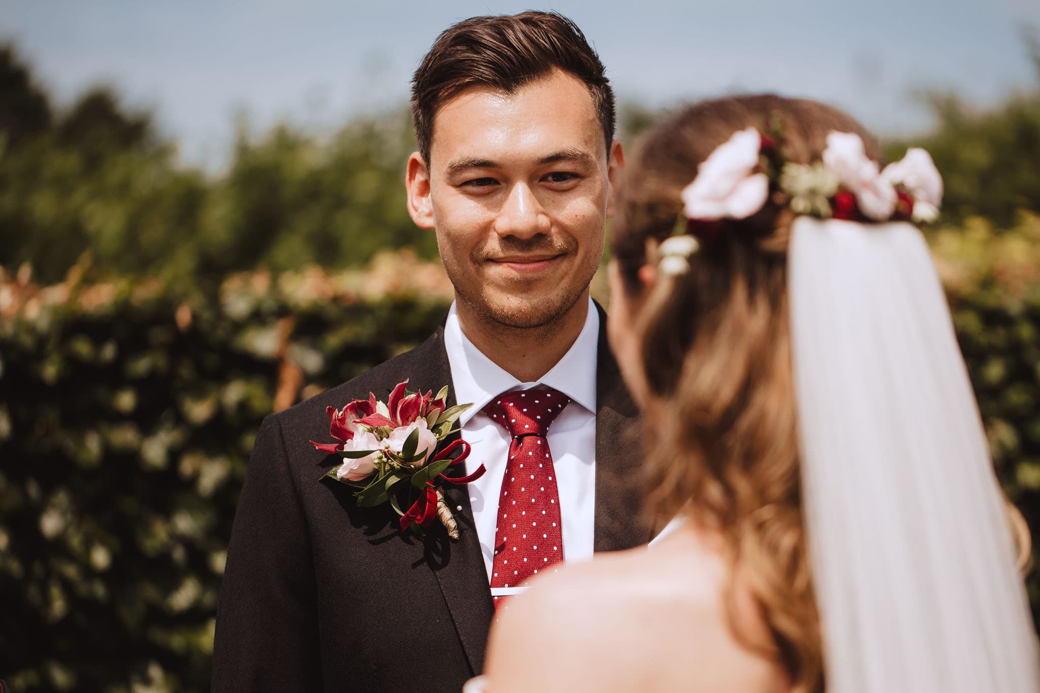 Close up of groom wearing red and pink button hole