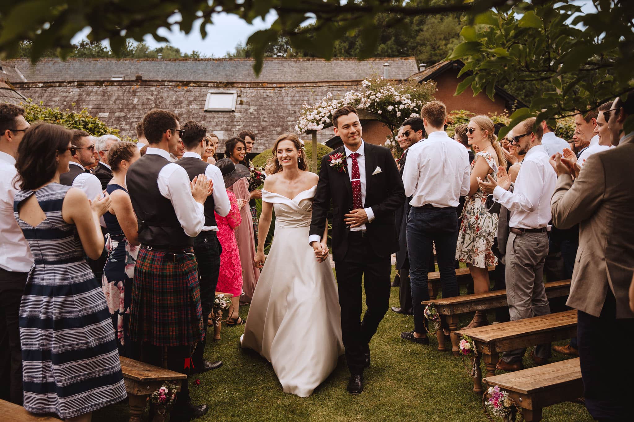 bride and groom exit their wedding ceremony at home in the garden