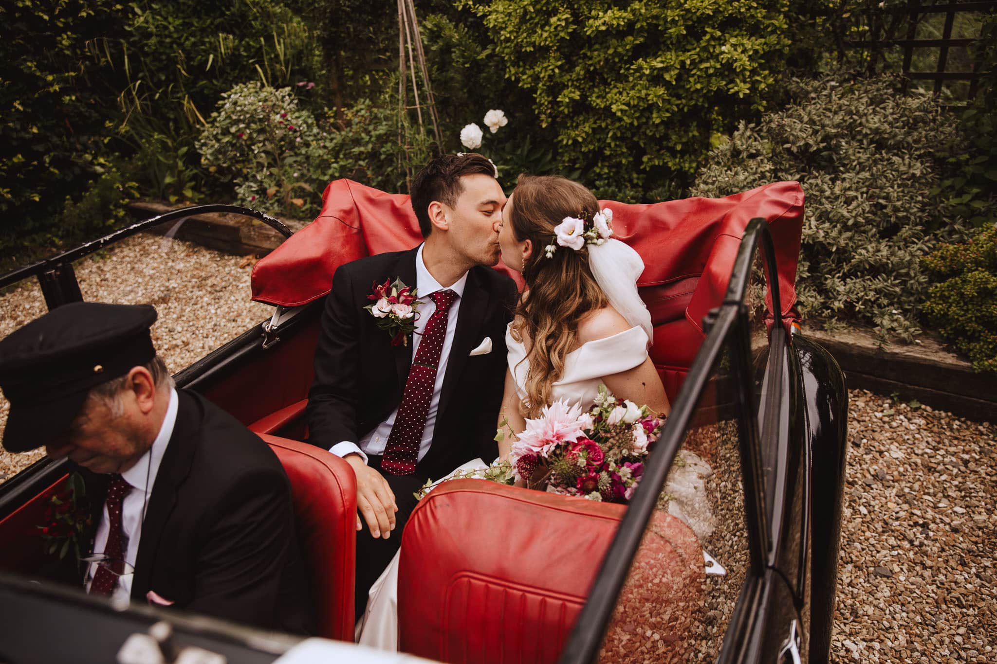 bride and groom share a kiss in the back of their Morris Minor