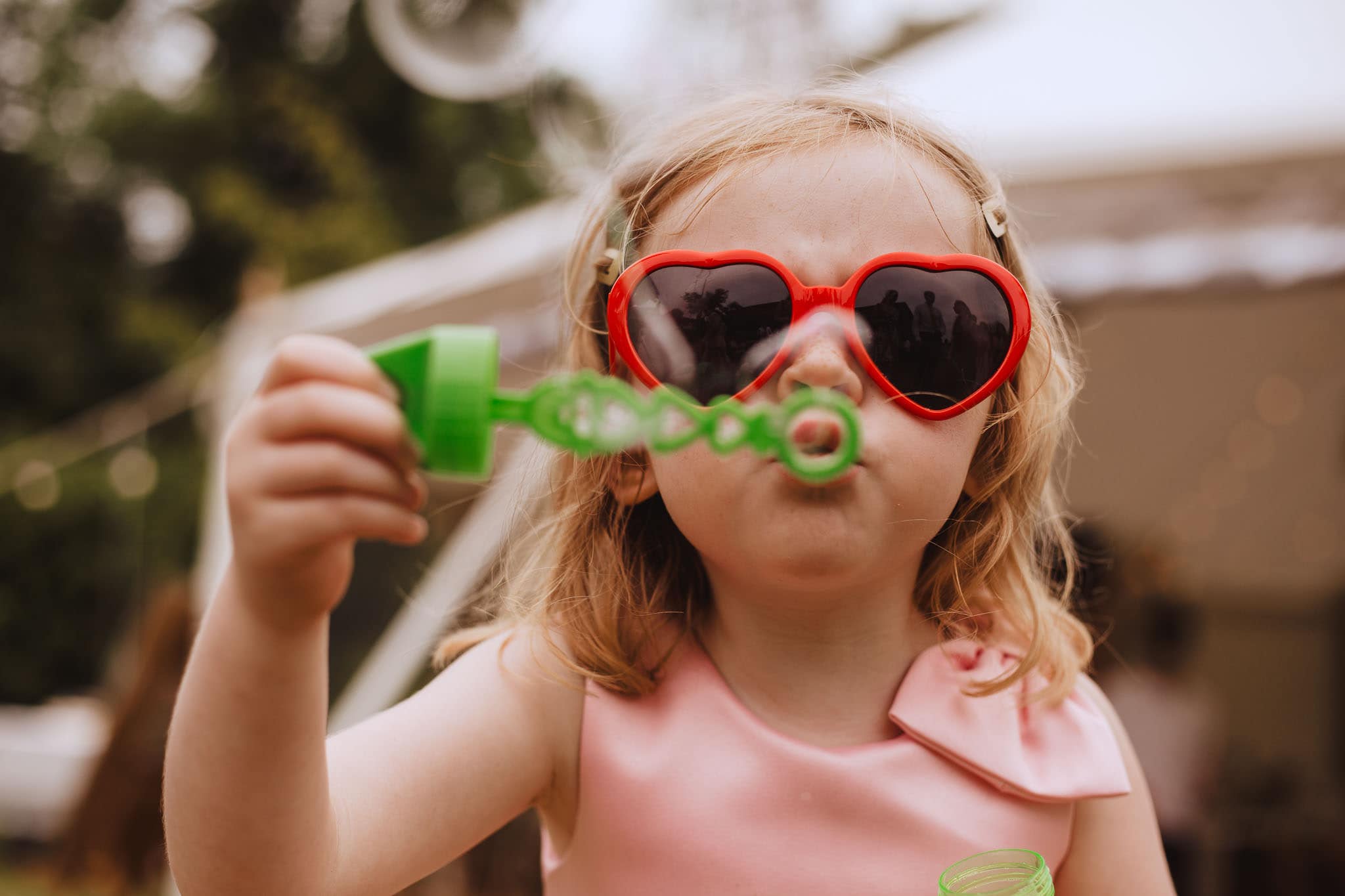 flower girl blowing bubbles in heart shaped sunglasses