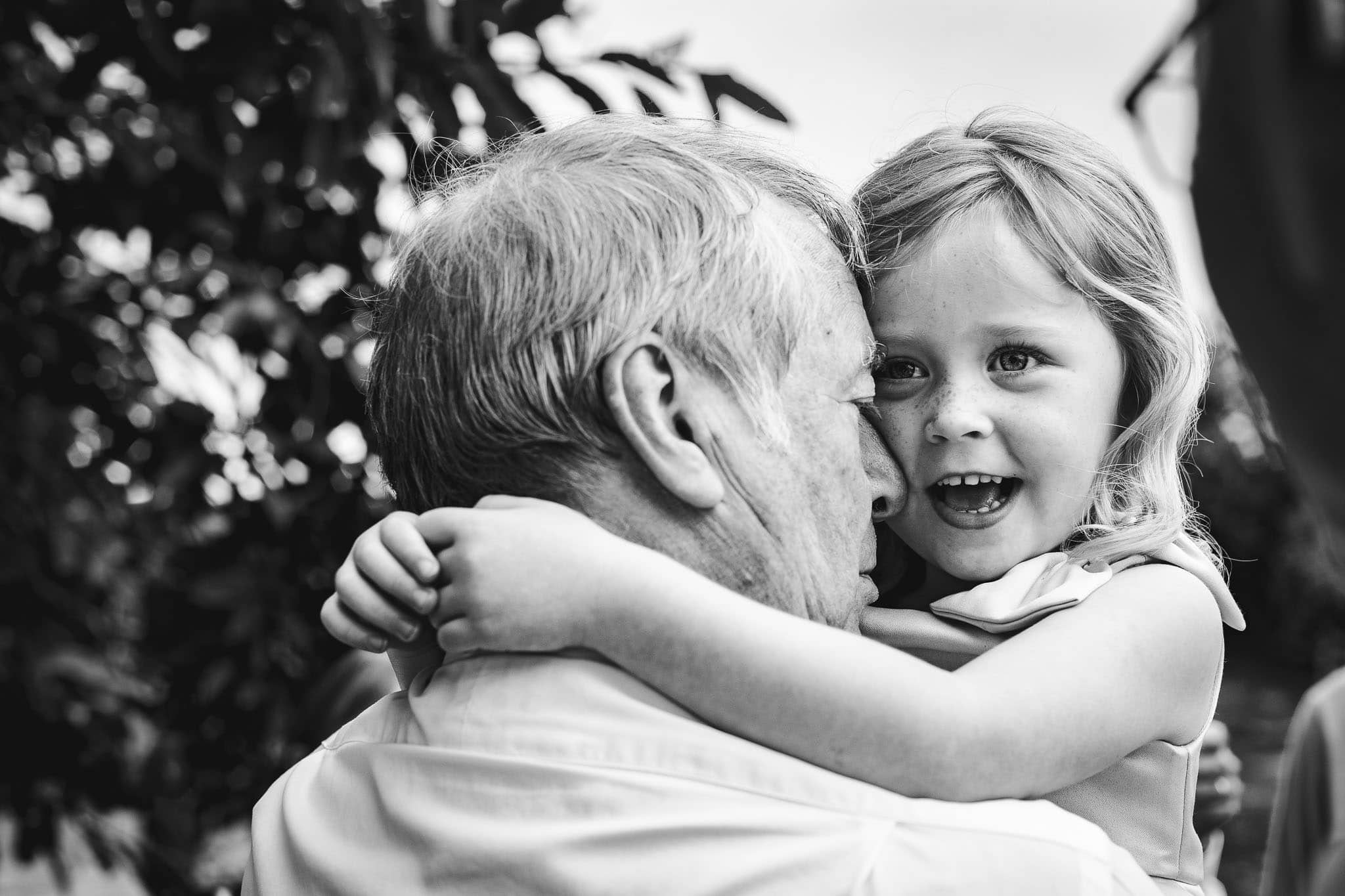 close up of grandad cuddling flower girl at a Marquee Wedding at Home