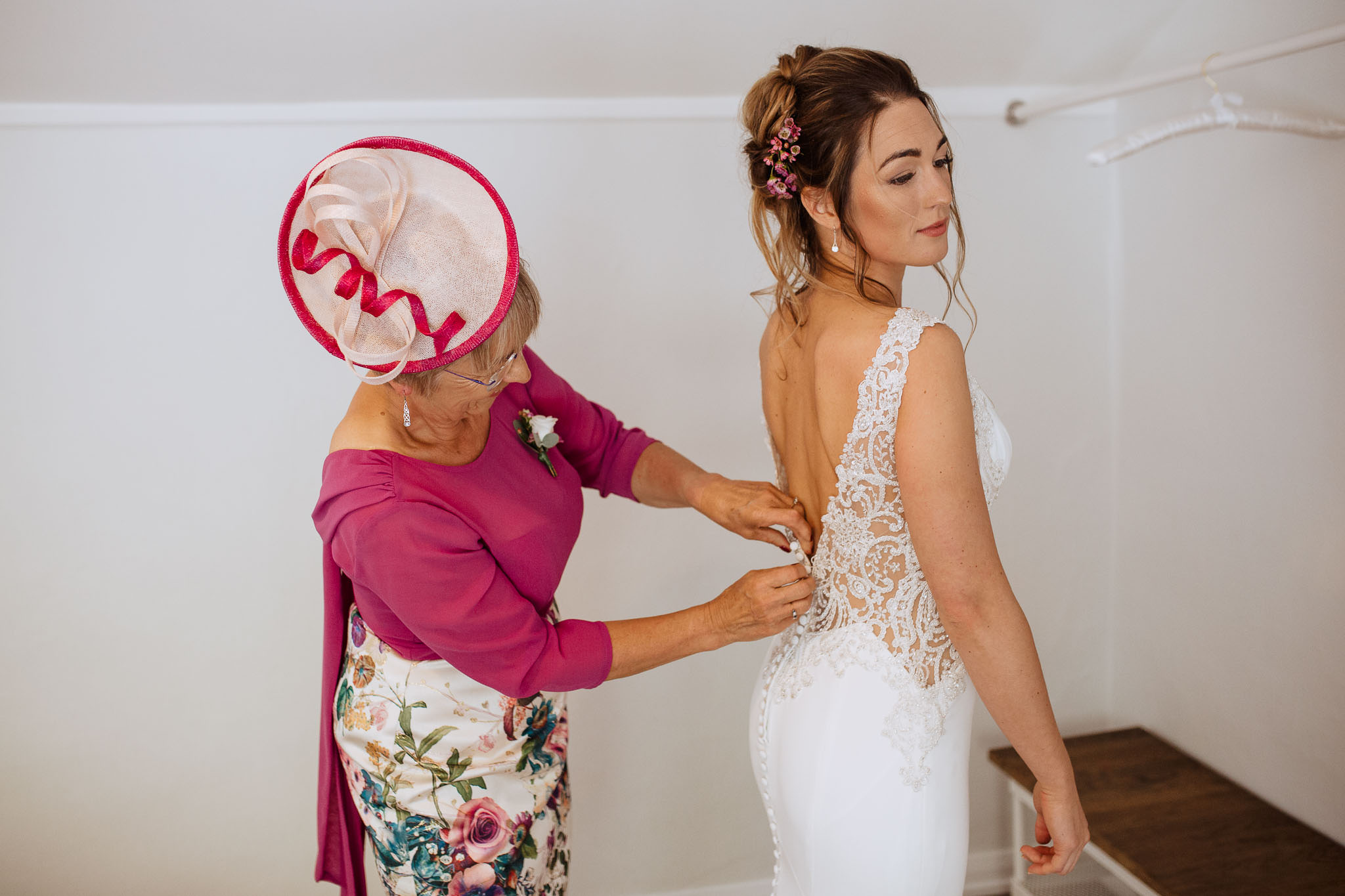 bride putting on her beaded low back wedding gown