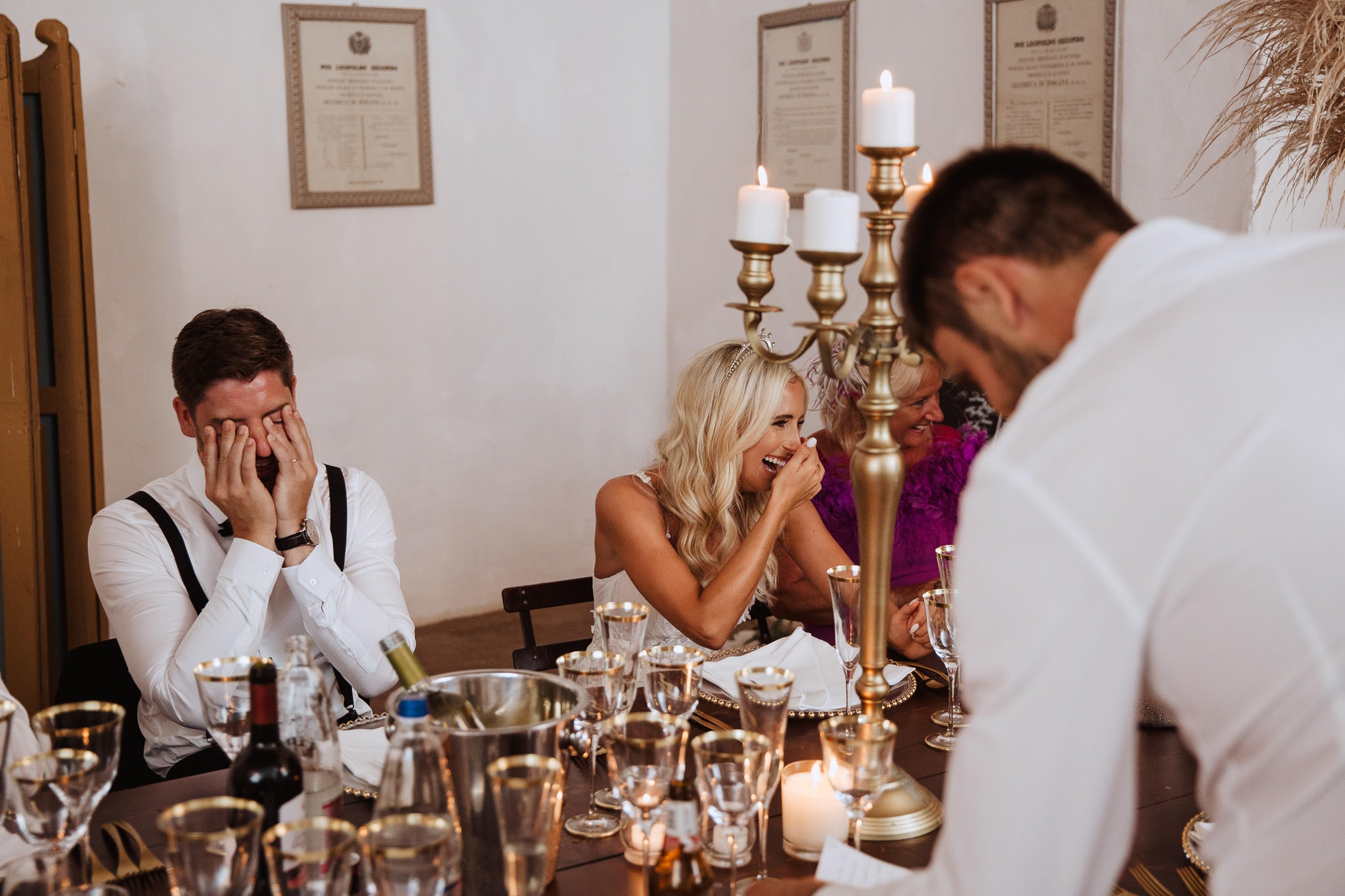 candid shot of bride and groom laughing at best man's speech