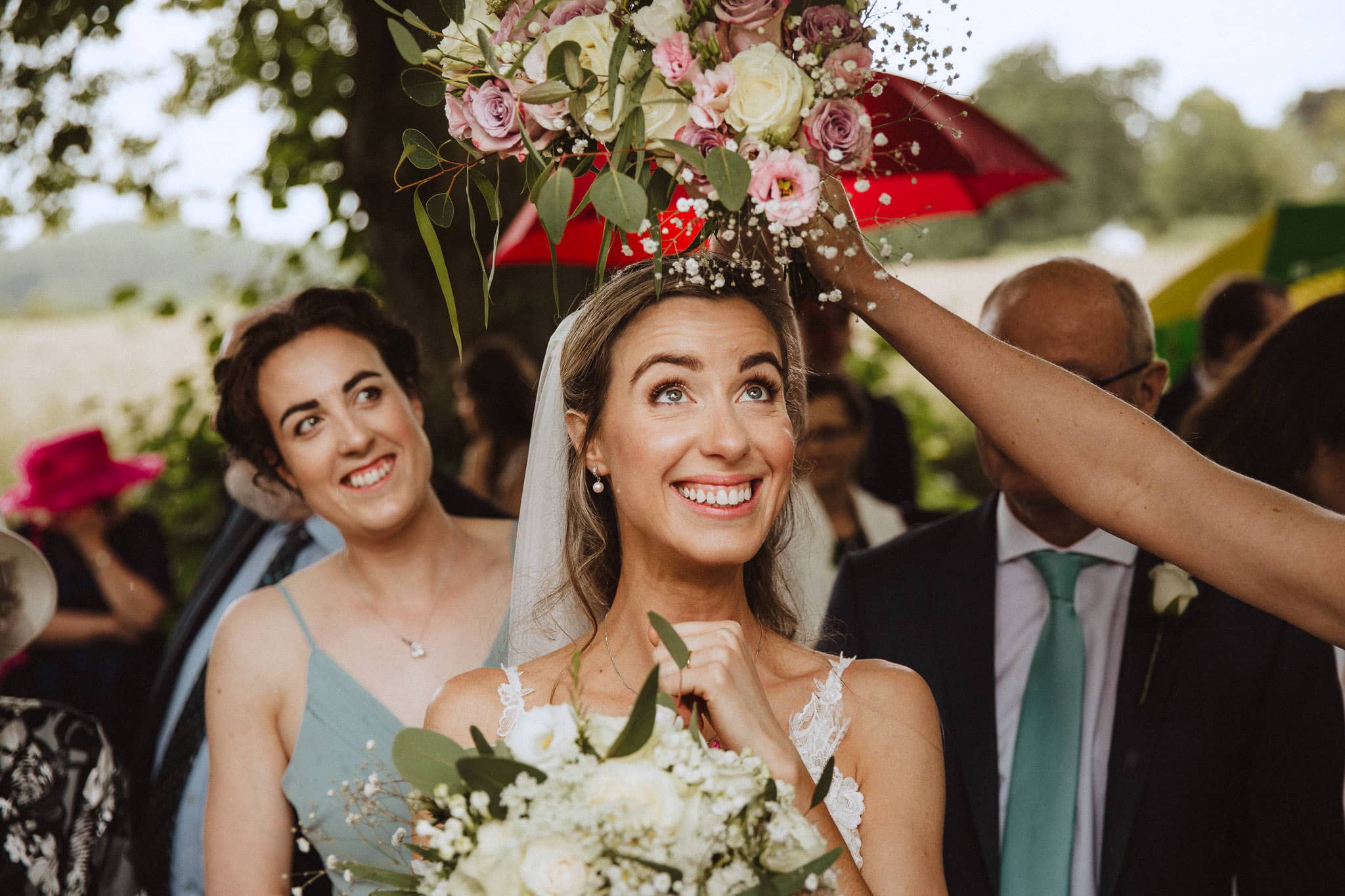 using the bouquet as an umbrella for a rainy day at a Leicestershire wedding