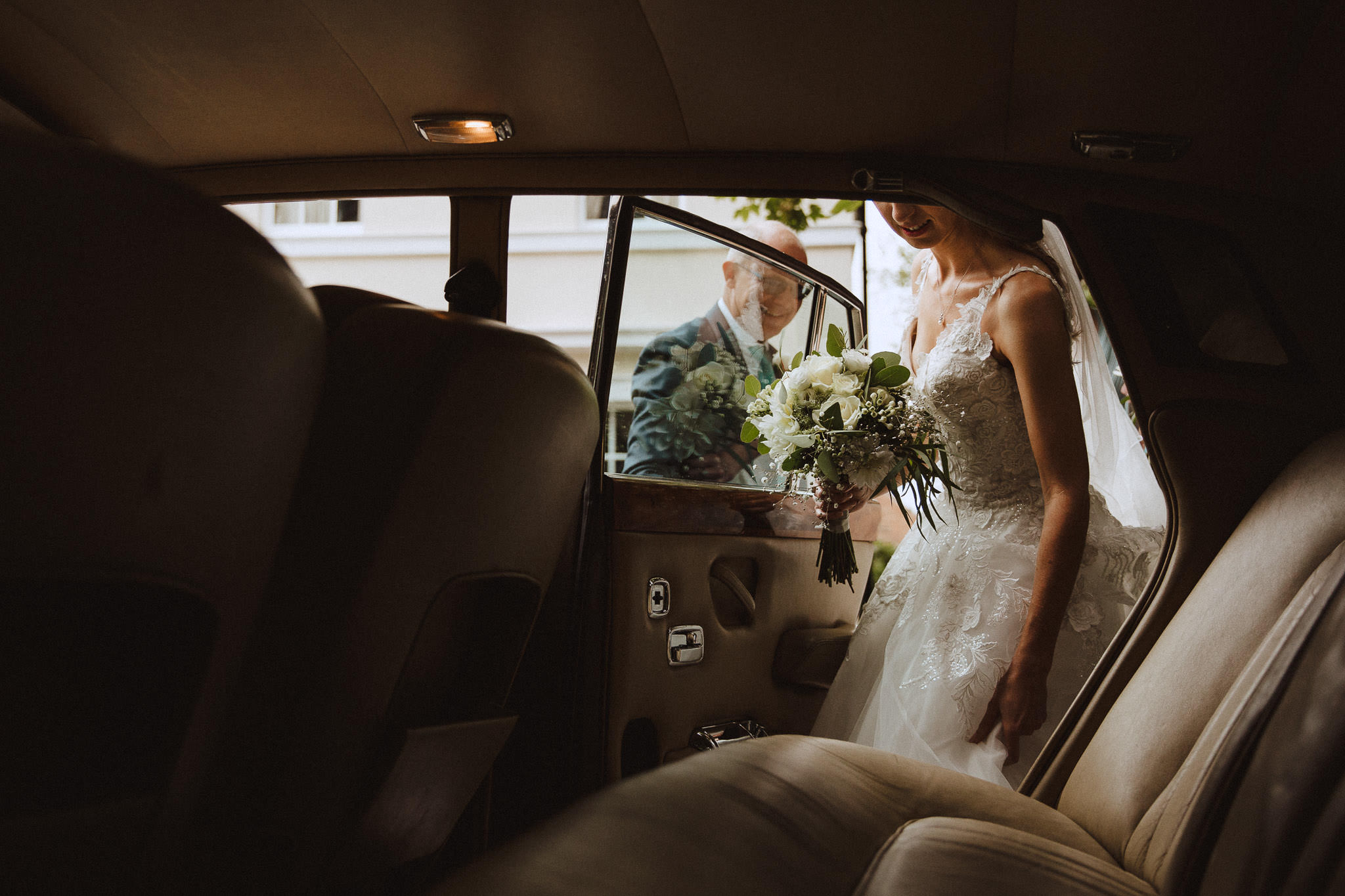 beautiful light as the bride gets into her wedding car