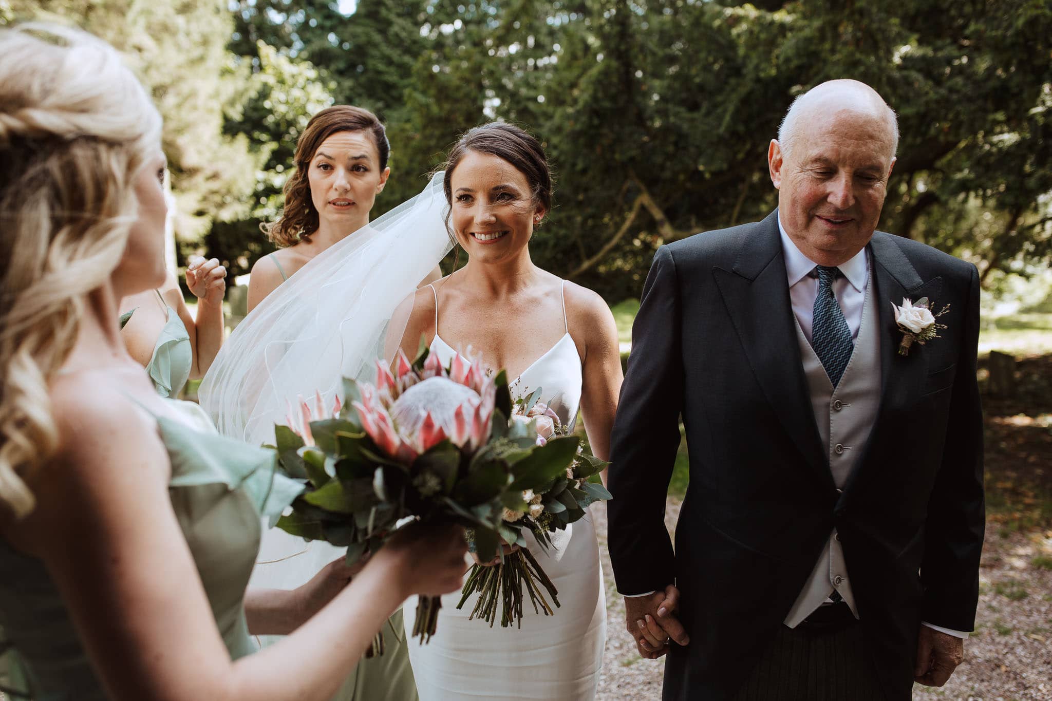 beautiful bride in Suzanne Neville dress waiting outside Church for Ashbourne Derbyshire Wedding