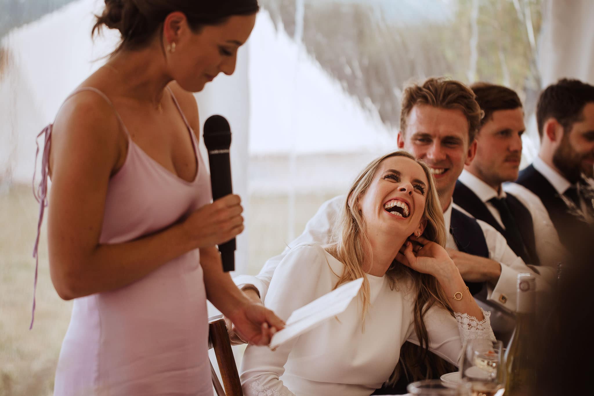 bride laughing at her bridesmaid's speech