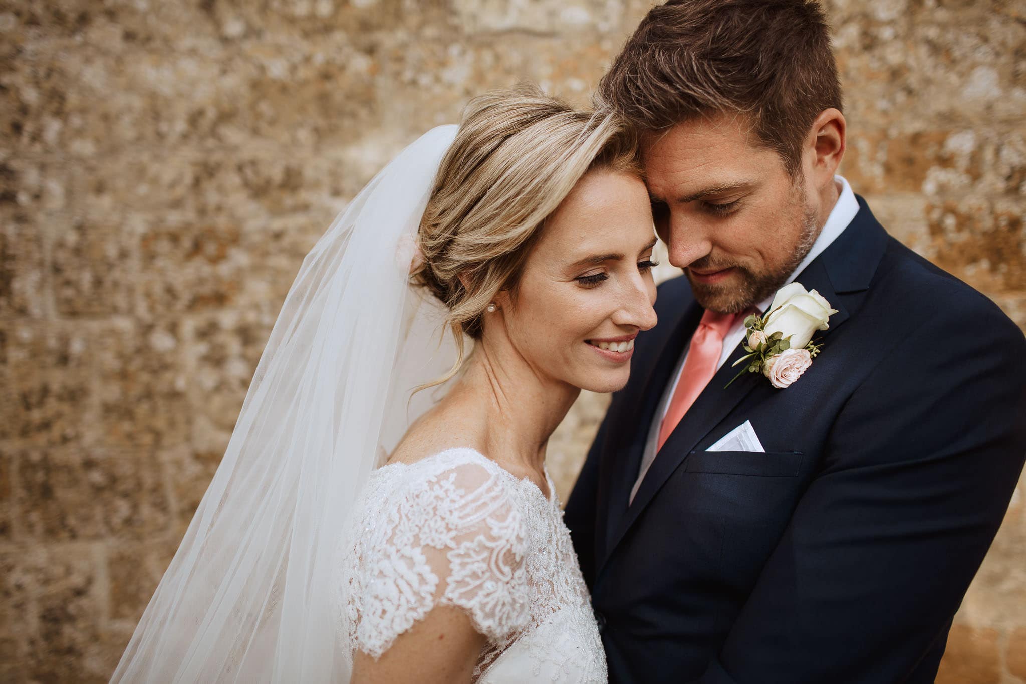 close up of bride and groom set against Cotswolds stone at Lapstone Barn