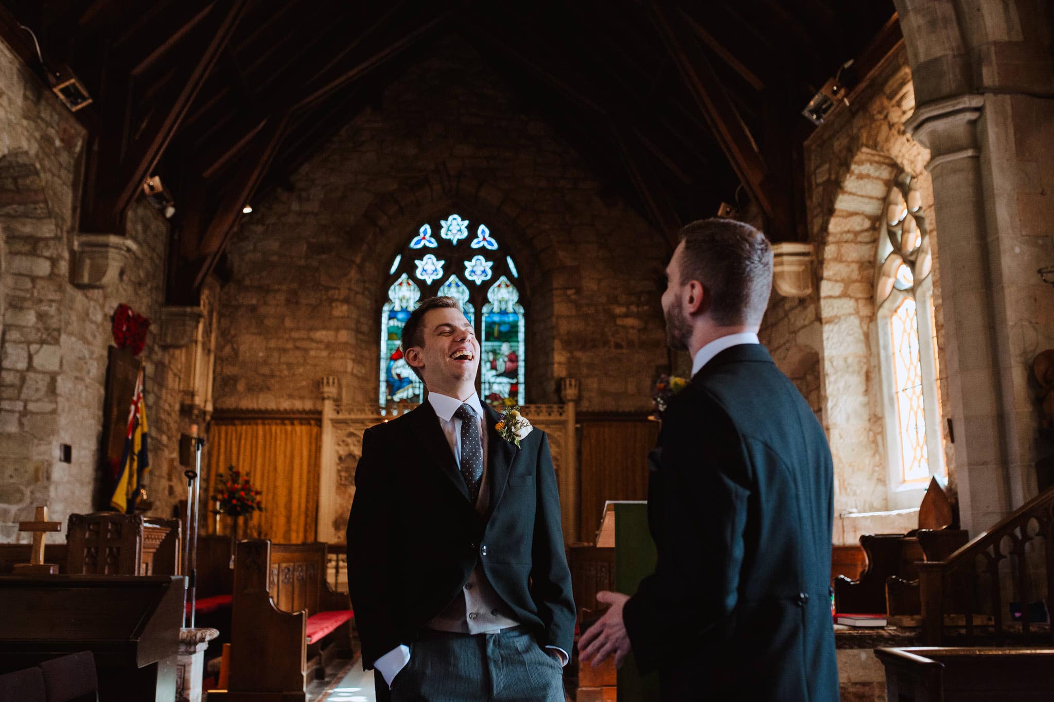 groom laughing in candid photo as he waits for the bride