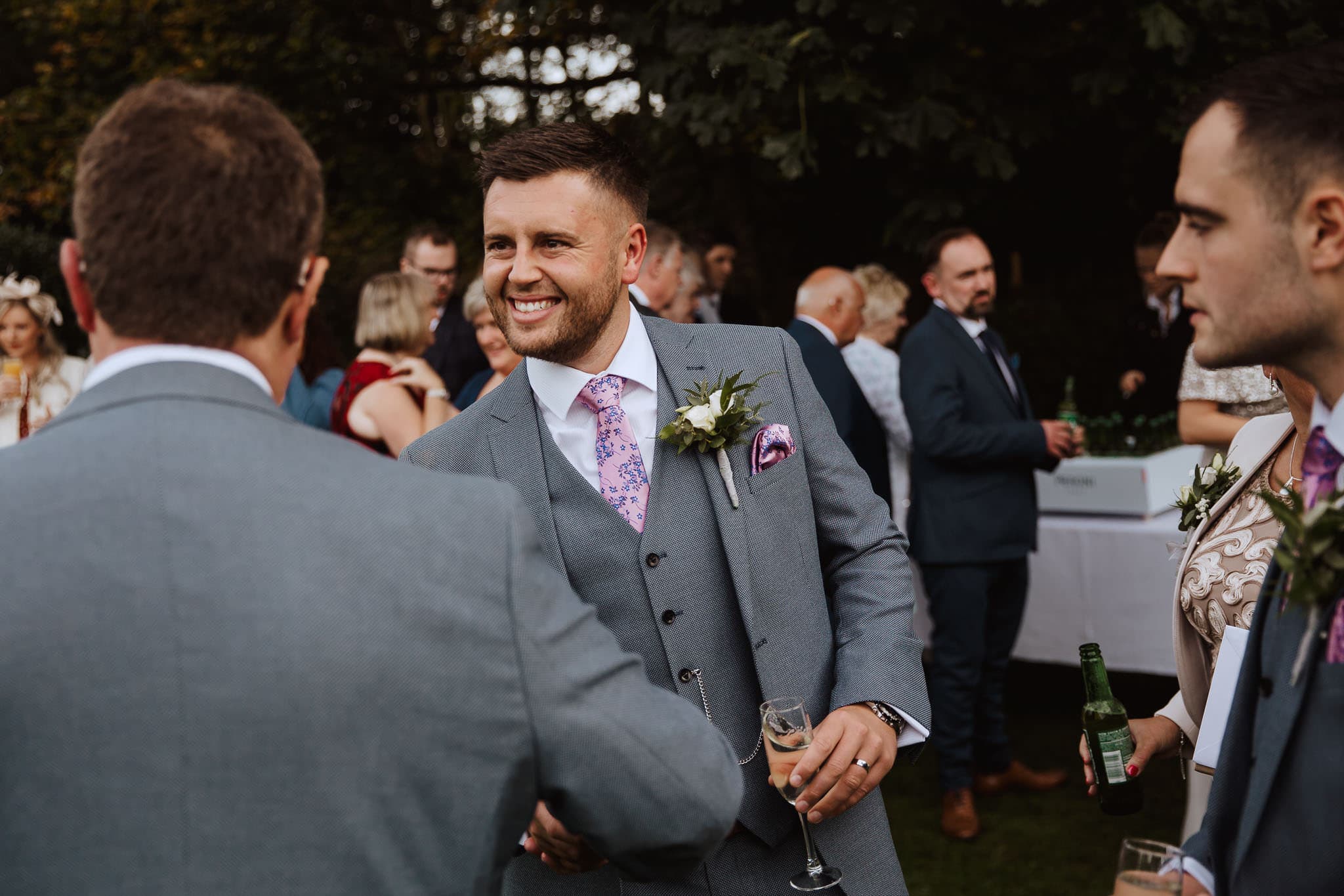 groom in grey suit greeting guests at Newton House Barns Wedding