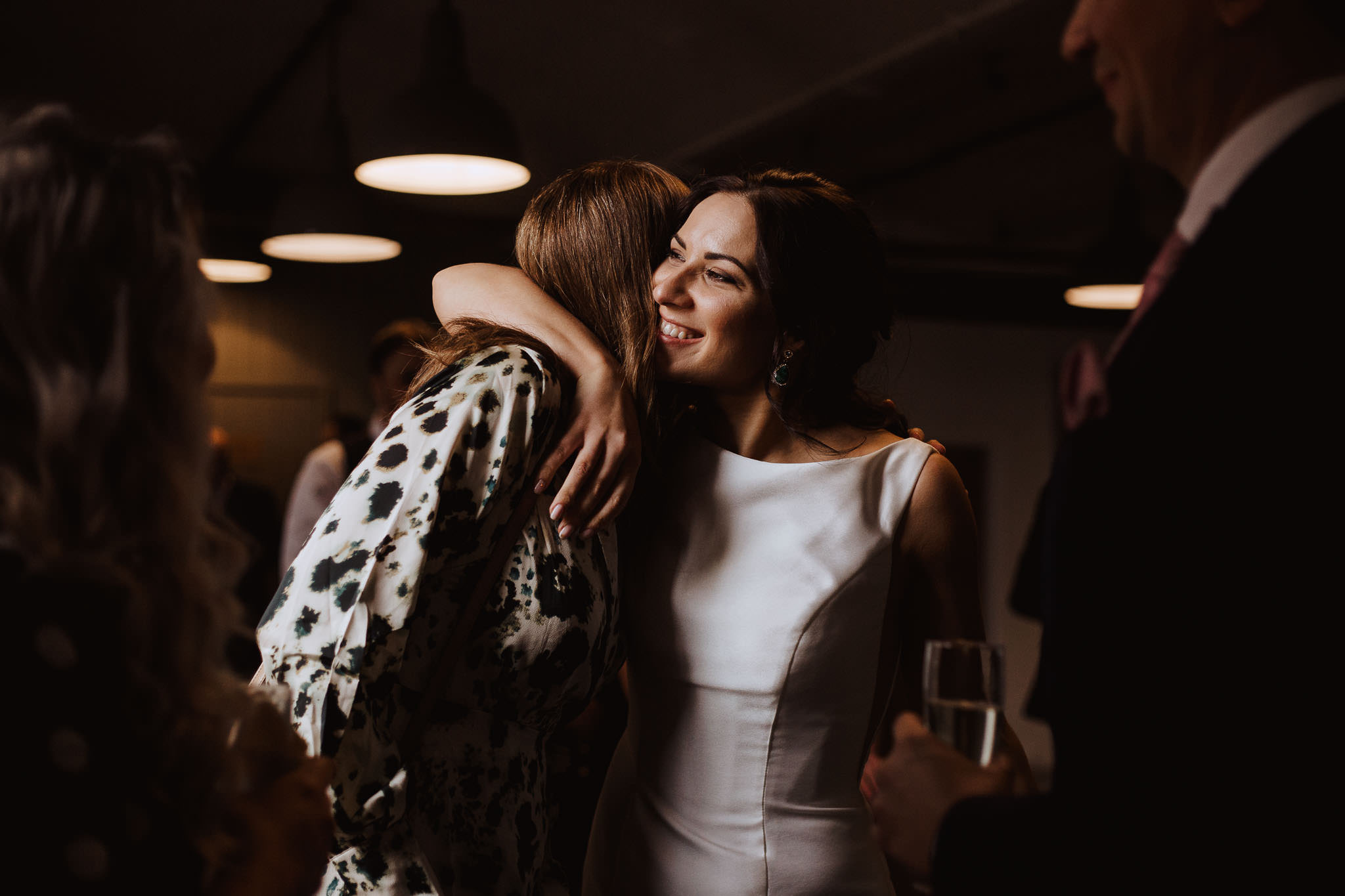 beautiful bride hugging friend caught in window light