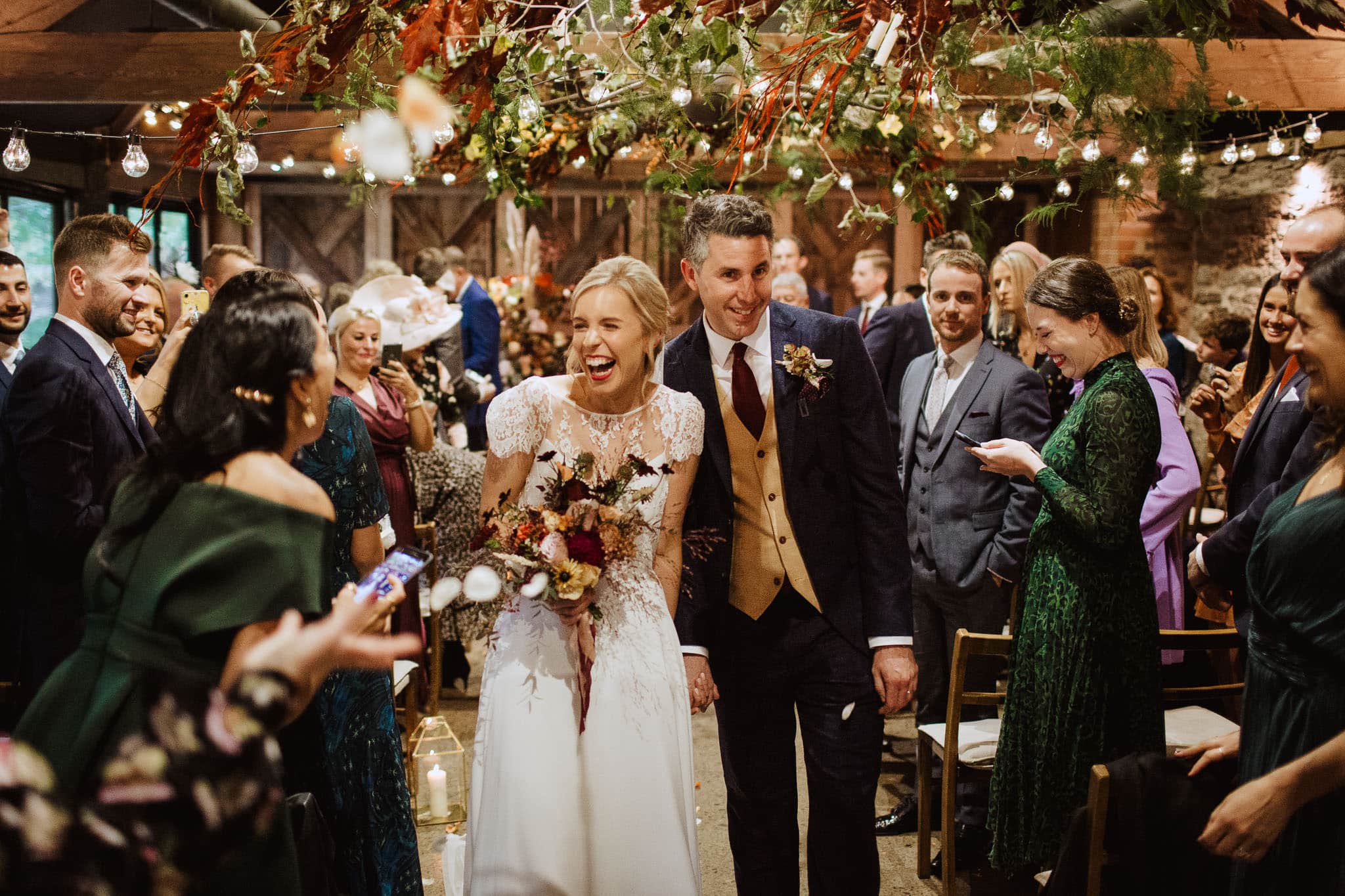 bride laughing as she walks down the aisle after her Dewsall Court, Herefordshire wedding