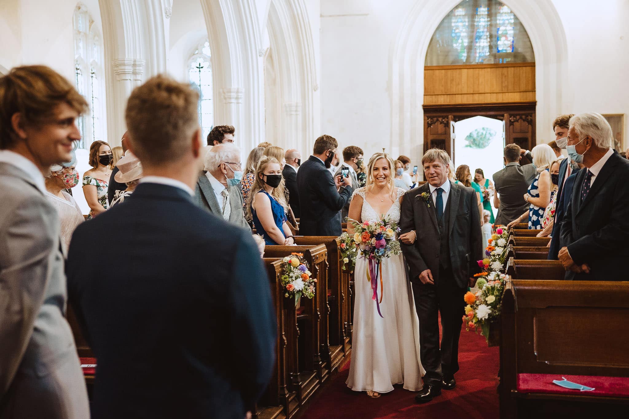 beautiful bride walking down the aisle with bright colourful bouquet 