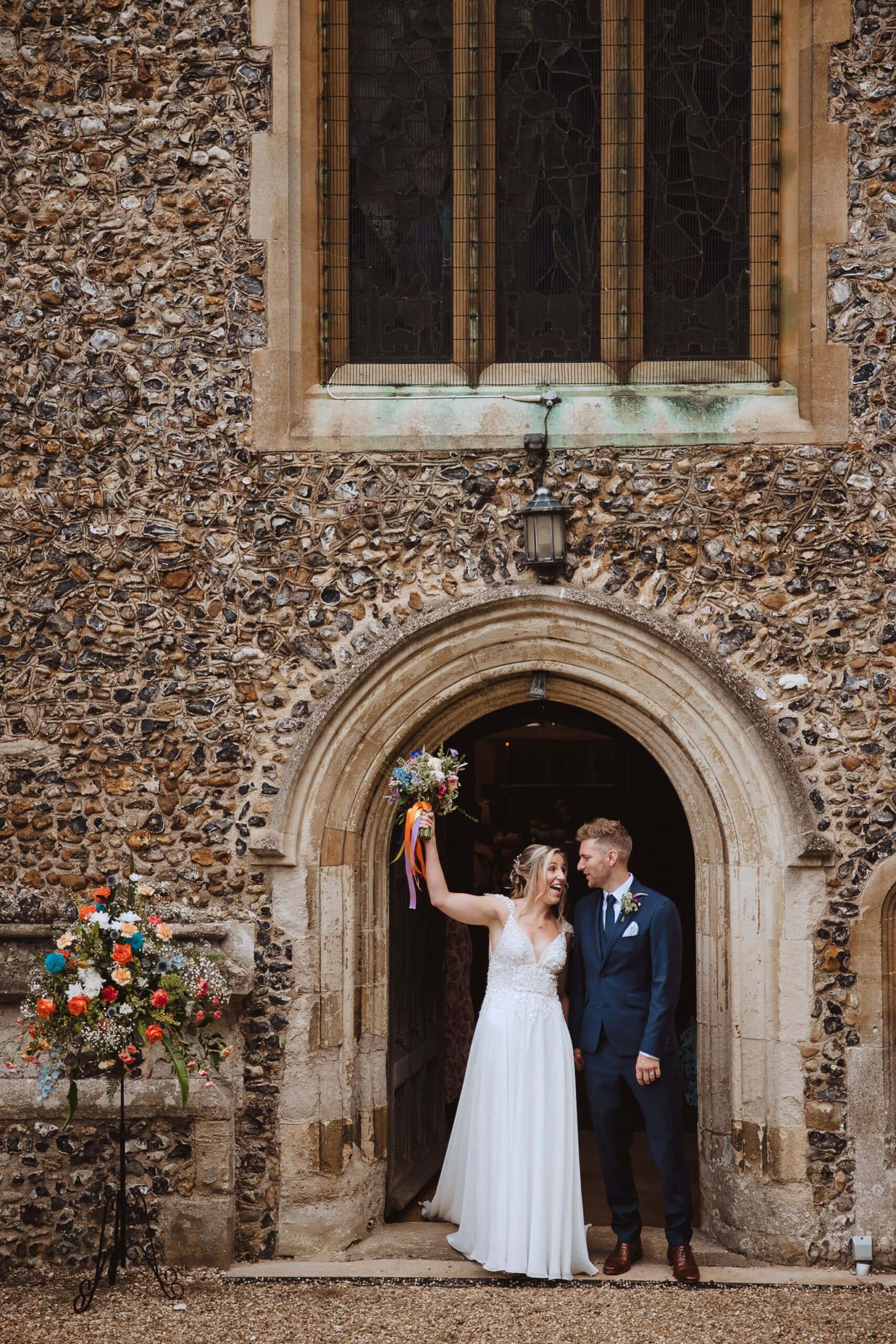 bride and groom cheering as they exit church