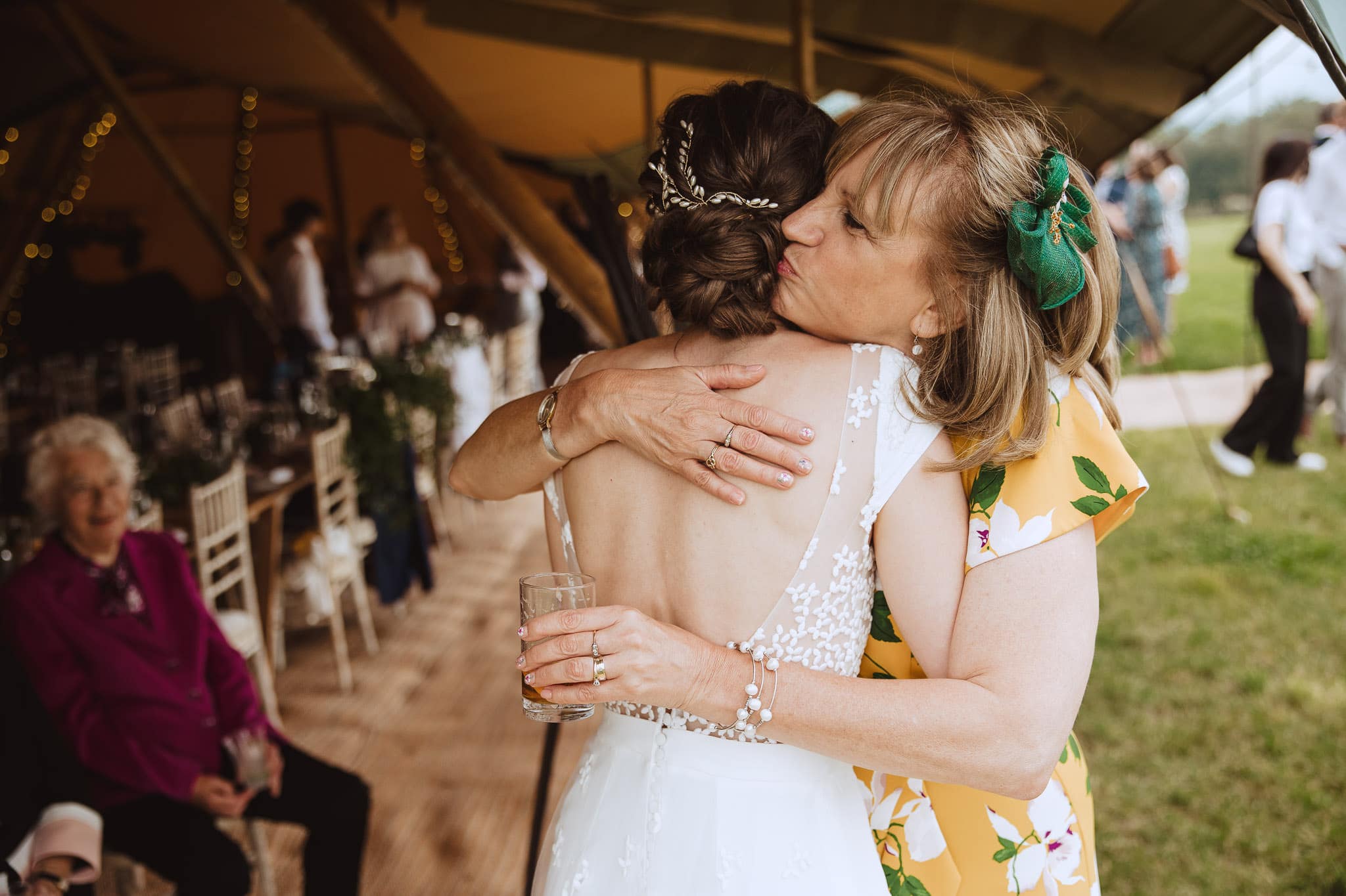 close up candid photo of bride hugging wedding guest at tipi wedding