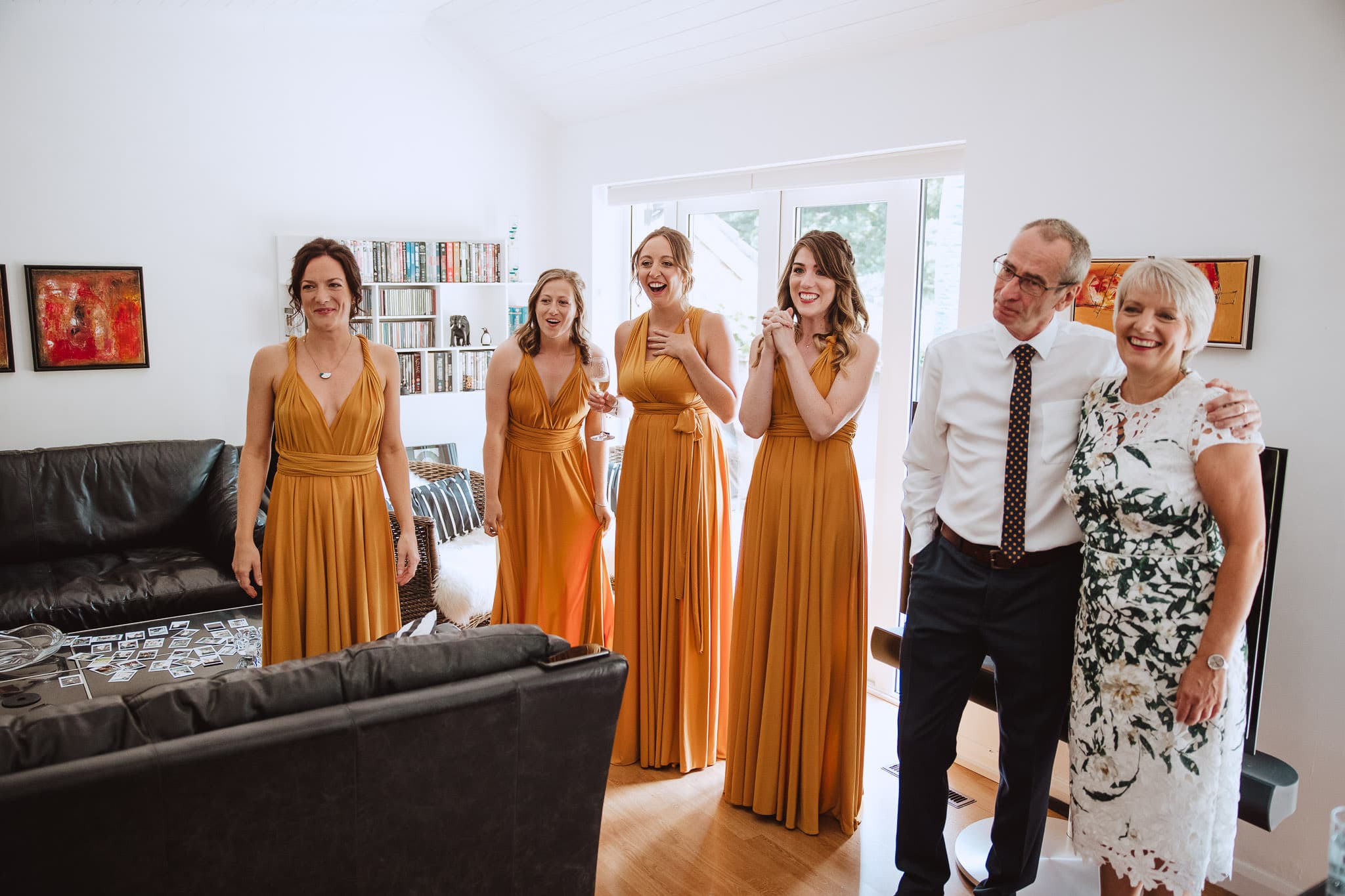 happy bridesmaids wearing mustard dresses and reacting to seeing the bride's dress