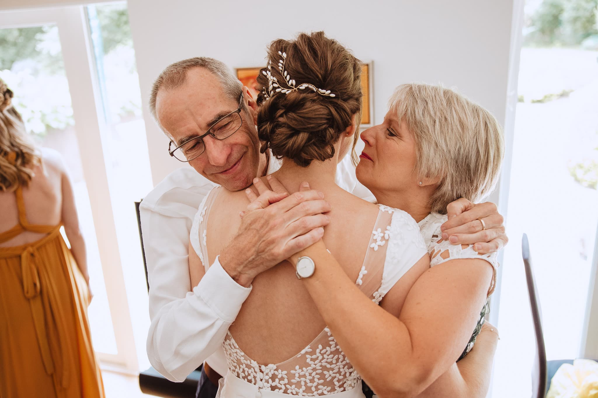 bride hugging her parents before her wedding ceremony