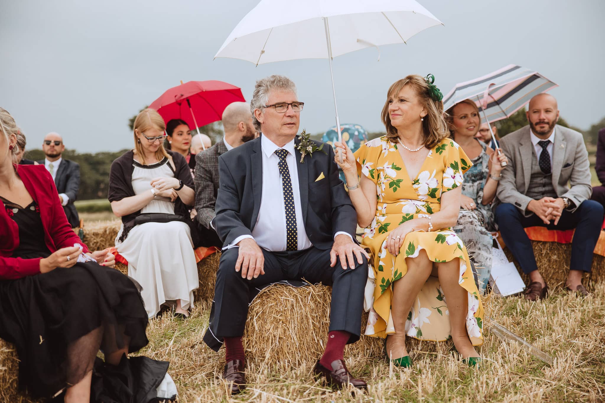 wedding guests seated on hay bales for outdoor wedding ceremony