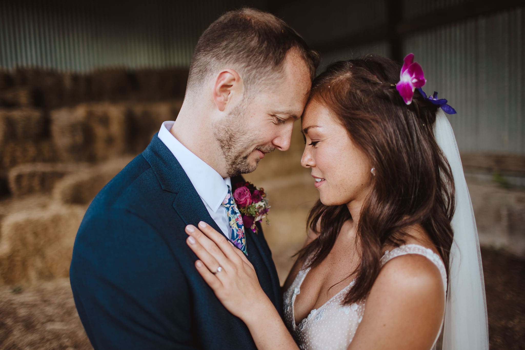 close up portrait of bride and groom amongst hay bales at farm wedding, Devon