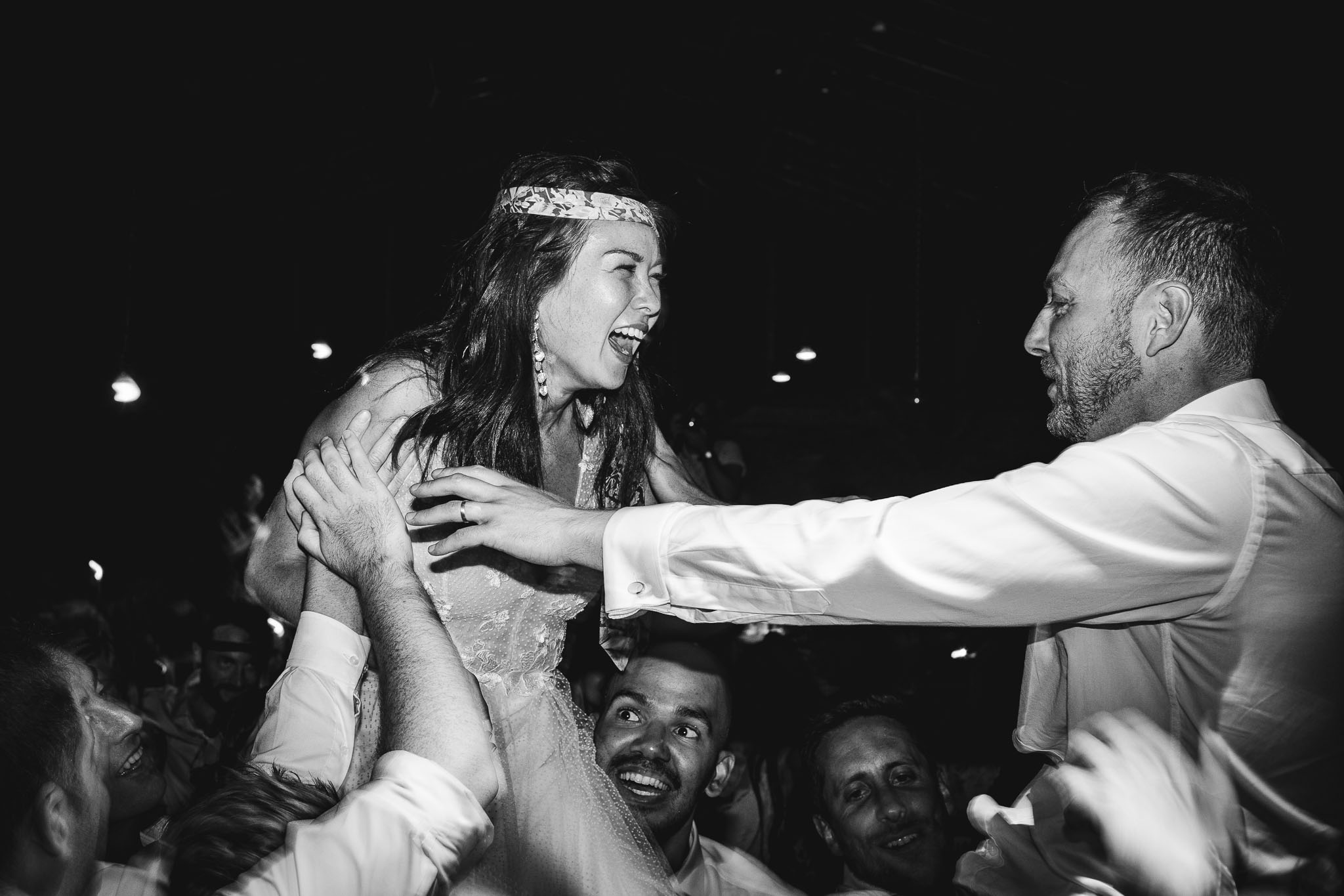 black and white photo of bride being lifted in the air on the dance floor