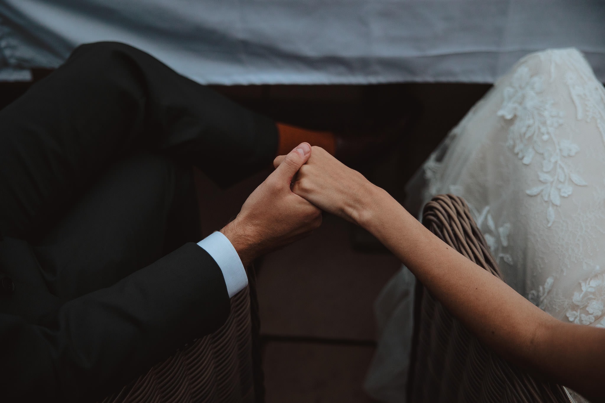 natural, intimate moment of bride and groom holding hands during wedding speeches